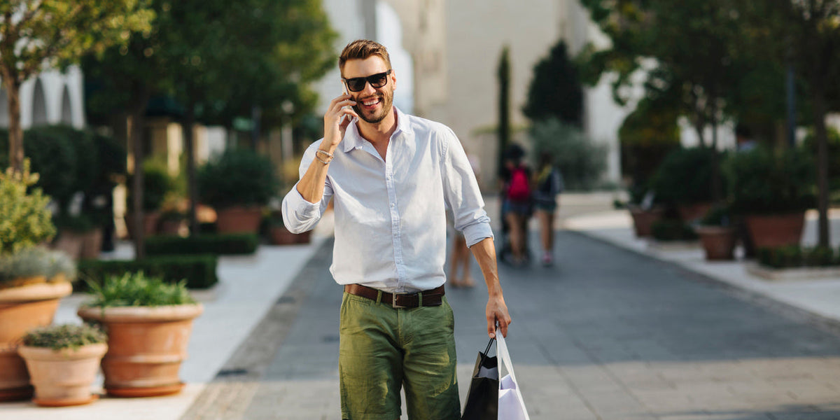 Homme en tenue décontractée portant des sacs de shopping, profitant des promotions mode masculine au centre-ville.