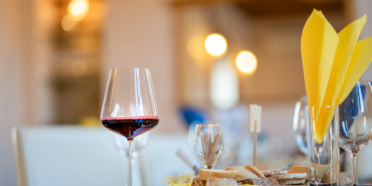 Glass of red wine with gourmet food selection at a fine dining table featuring artisanal gourmet foods LUXTORE.