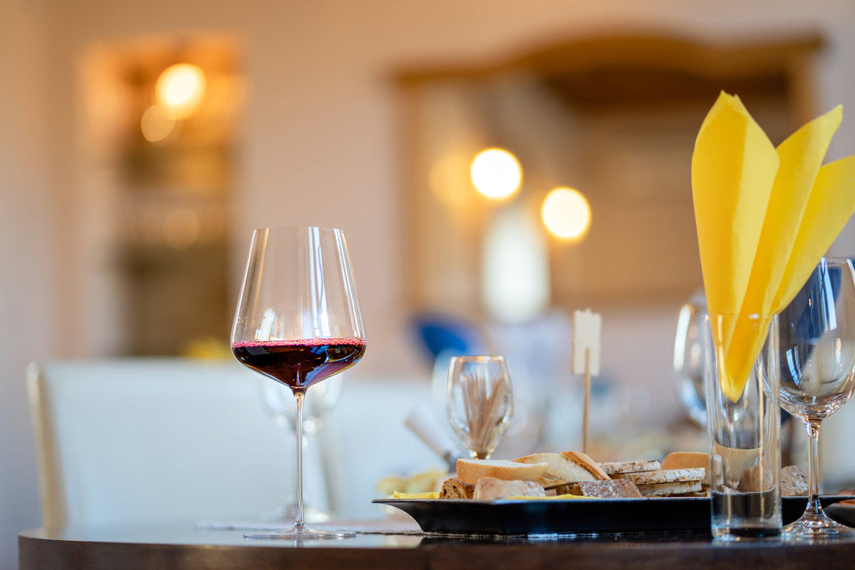 Glass of red wine with gourmet food selection at a fine dining table featuring artisanal gourmet foods LUXTORE.