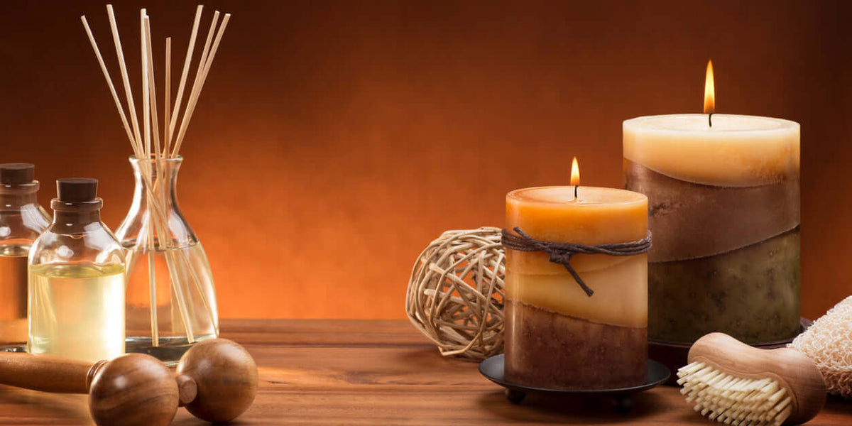 Luxury scented candles and diffusers on a wooden table with essential oils and scented sticks.