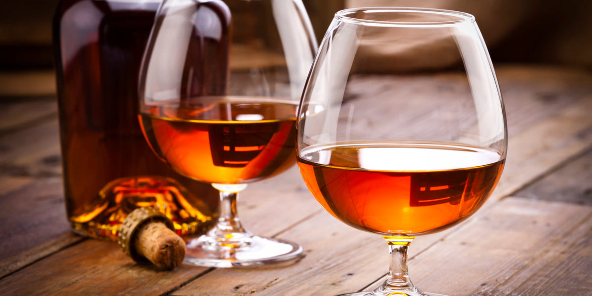 Verres de alcools fins et accessoires raffinés sur une table en bois, accompagnés d'une bouteille.