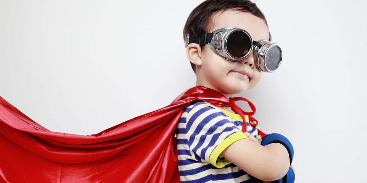 Enfant portant une cape rouge et des lunettes, illustrant l'élégance de la collection d'elegant boys clothing.