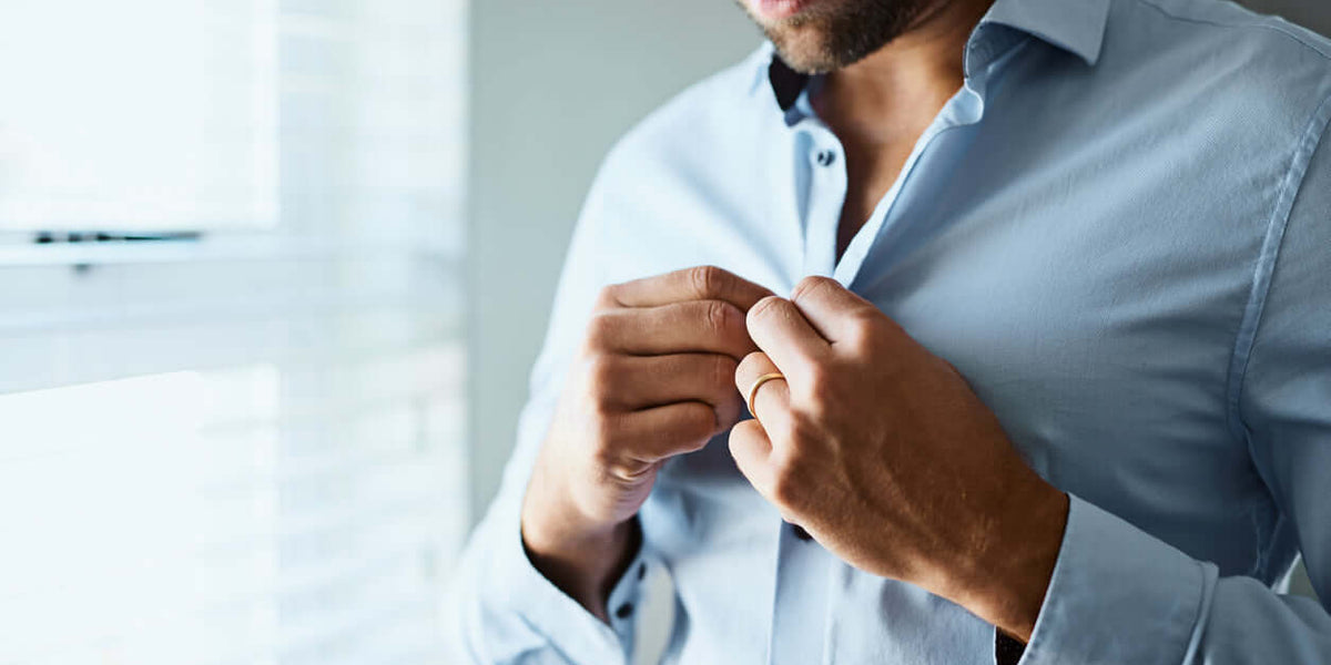 Man buttoning elegant shirt from the elegant men's shirts collection at LUXTORE.