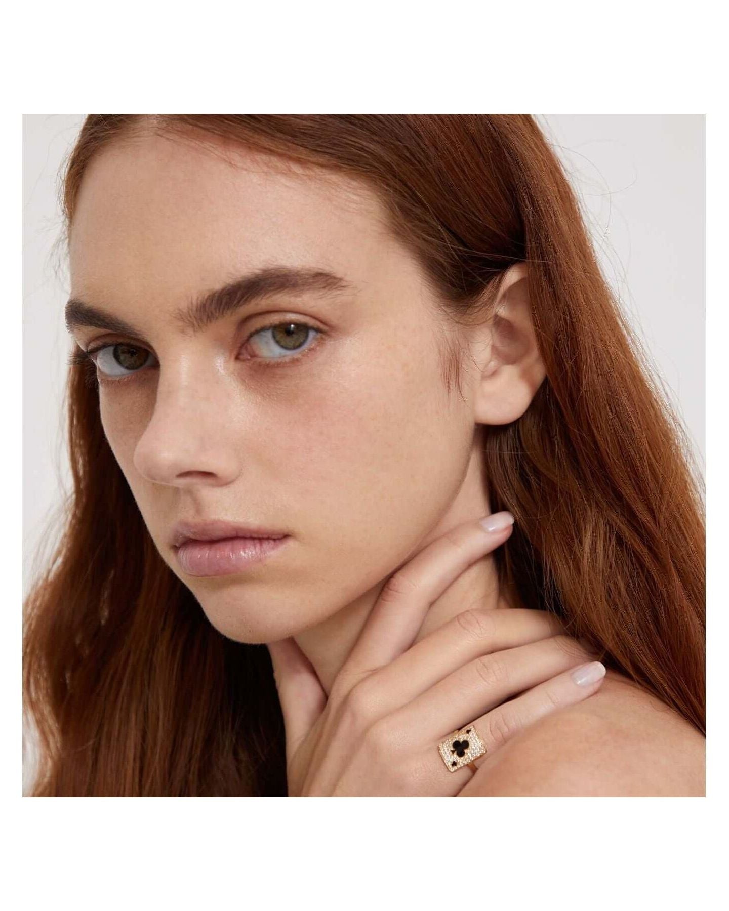 Woman wearing a pinkie ring with intricate design, showcasing elegance and style.