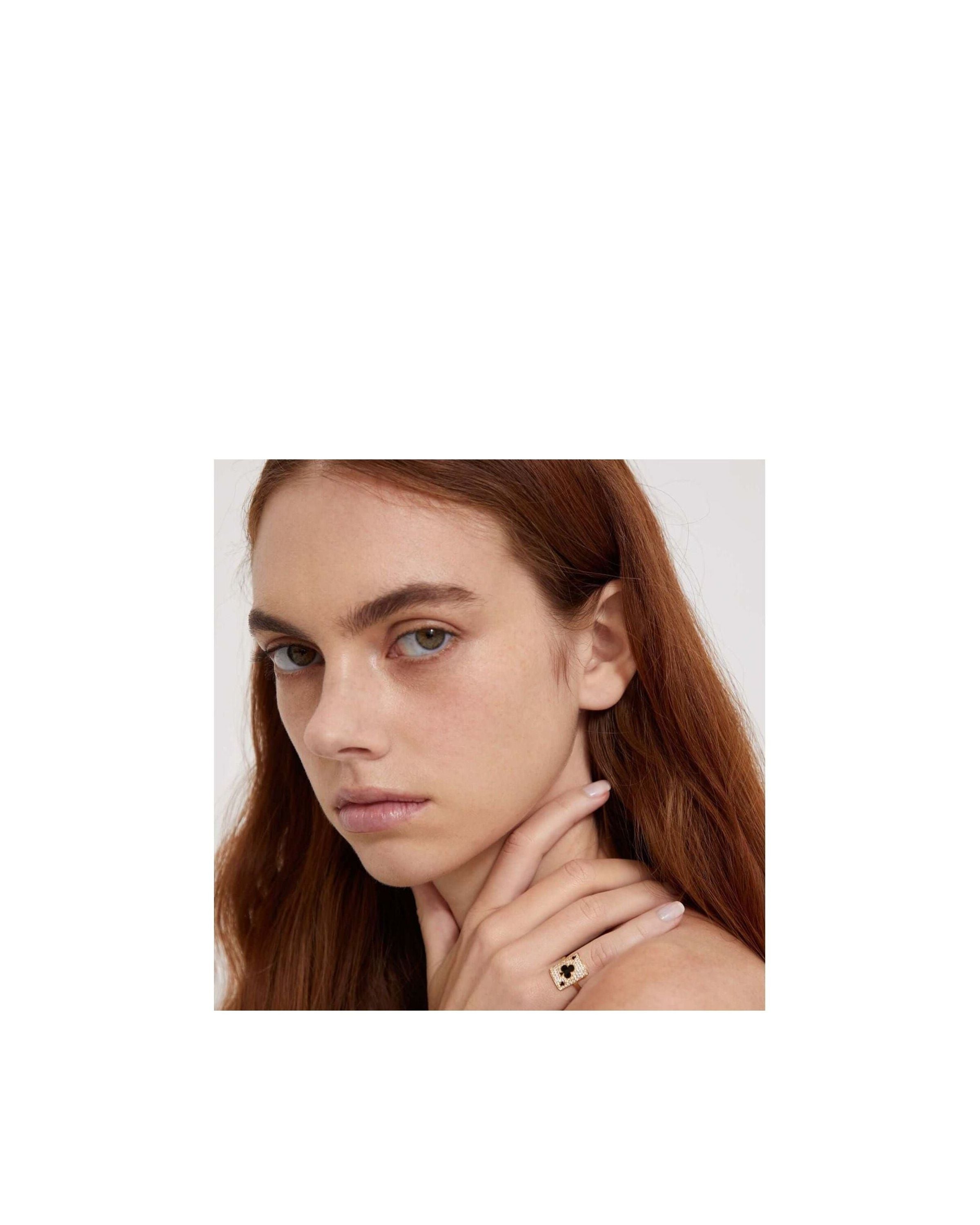 Woman wearing a pinkie ring with intricate design, showcasing elegance and style.