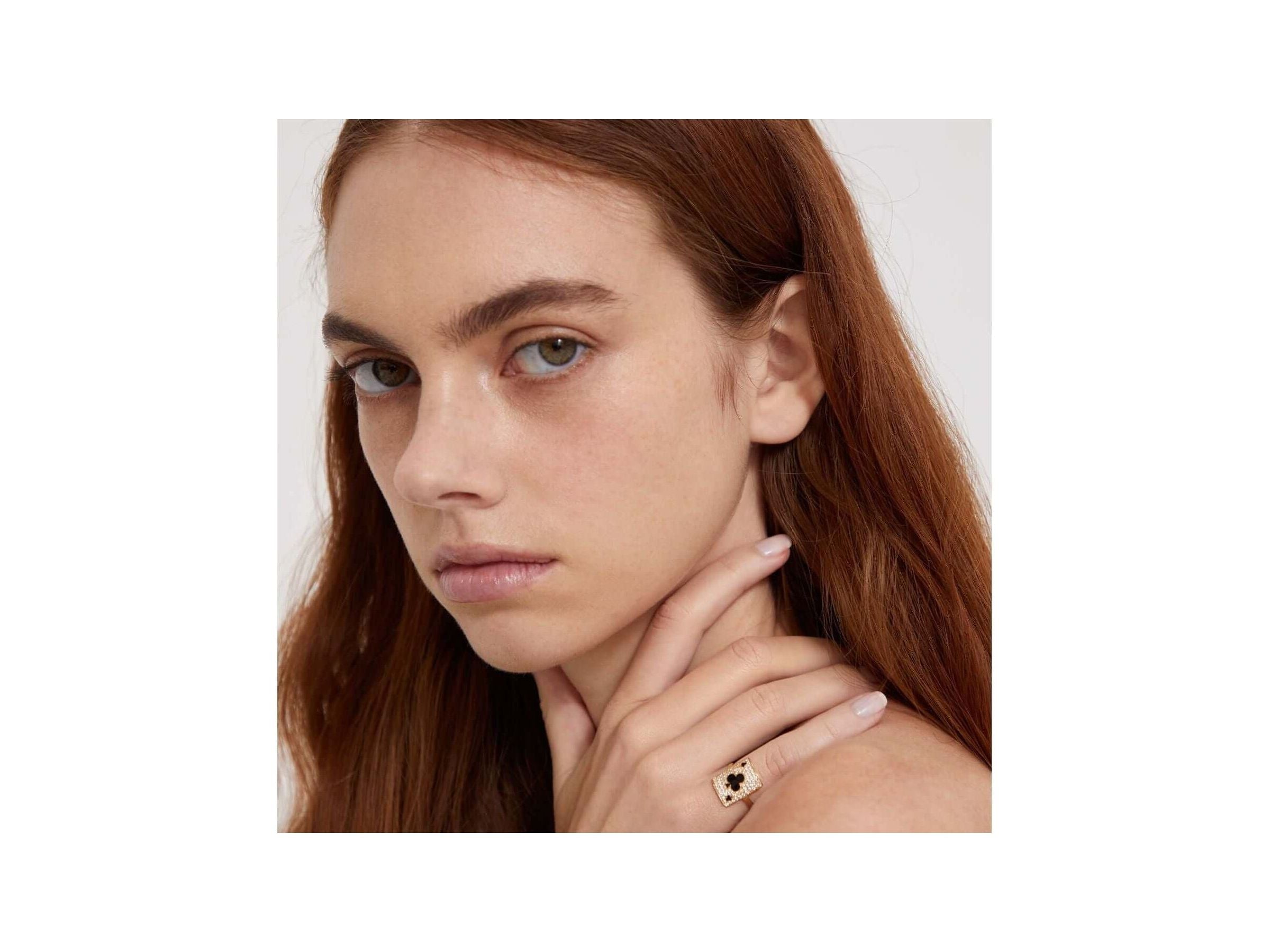 Woman wearing a pinkie ring with intricate design, showcasing elegance and style.