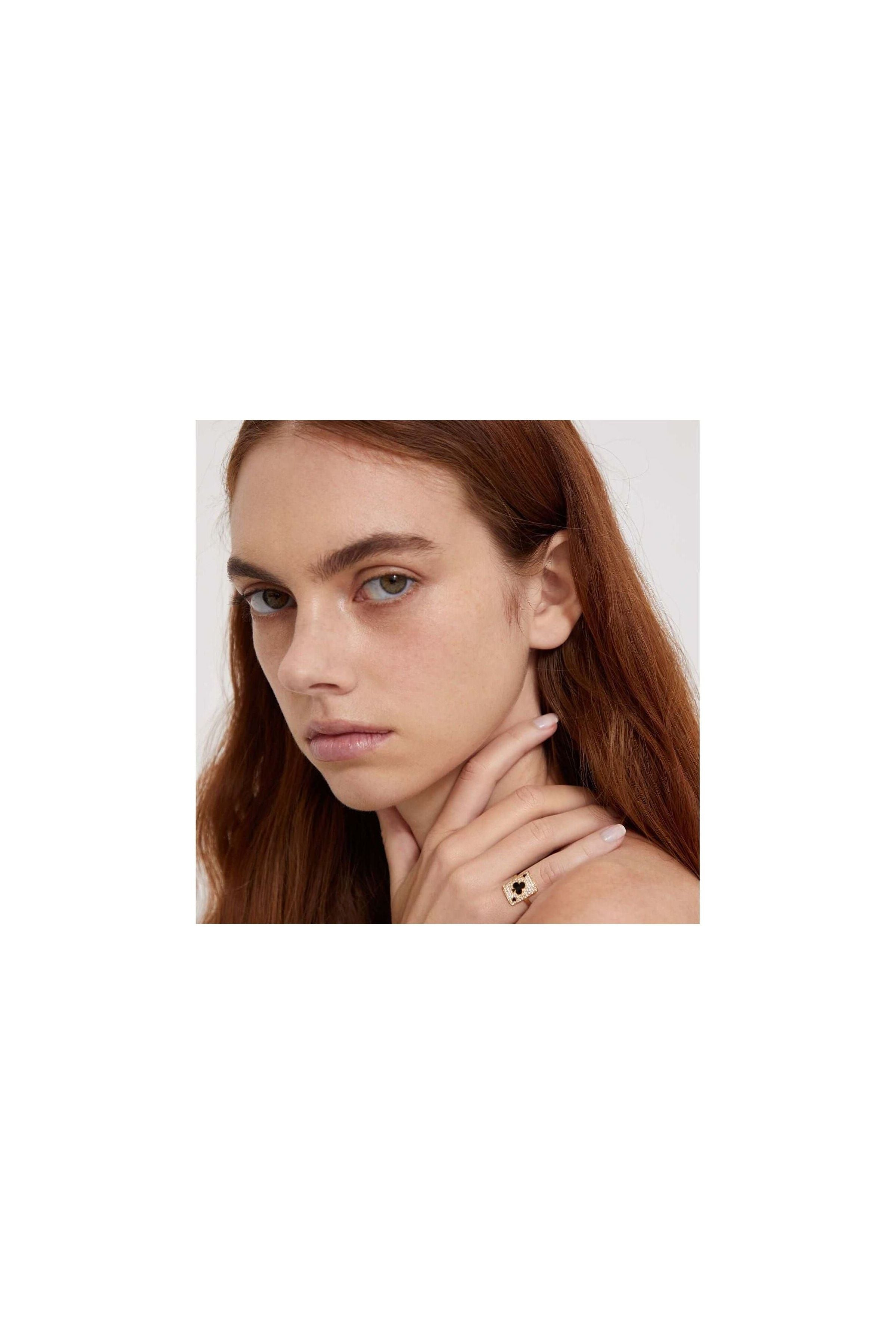 Woman wearing a pinkie ring with intricate design, showcasing elegance and style.