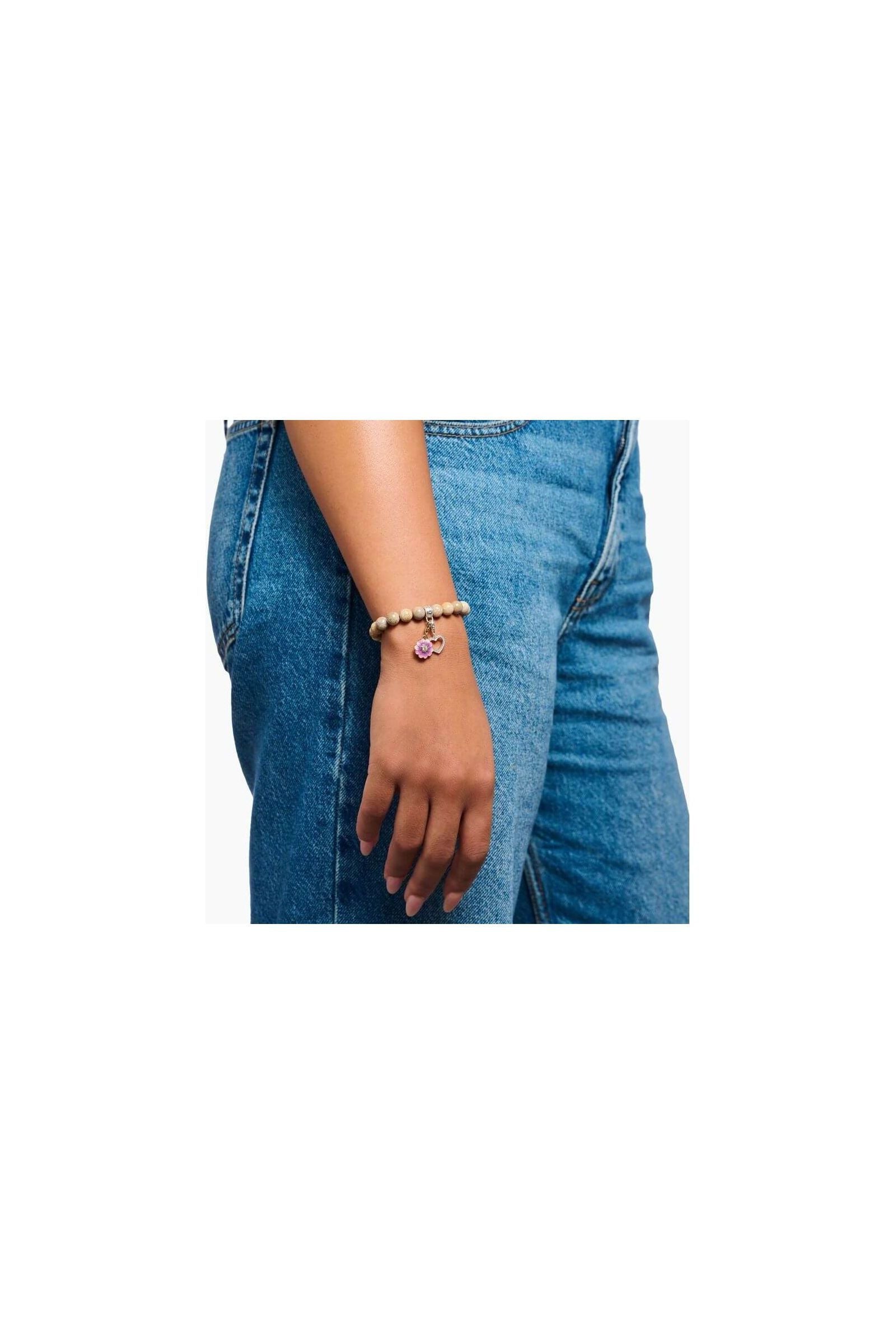 Bracelet with pink charm on woman's wrist, featuring beads and floral design, perfect for Charm Club jewelry.