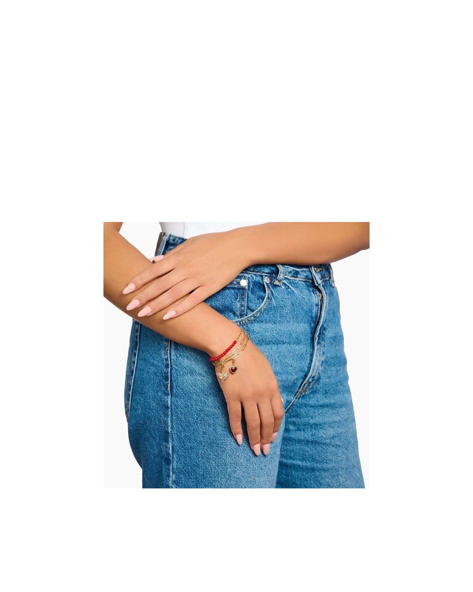 Femme portant un bracelet ajusté avec des perles rouges et un coeur, sur un fond en jeans.