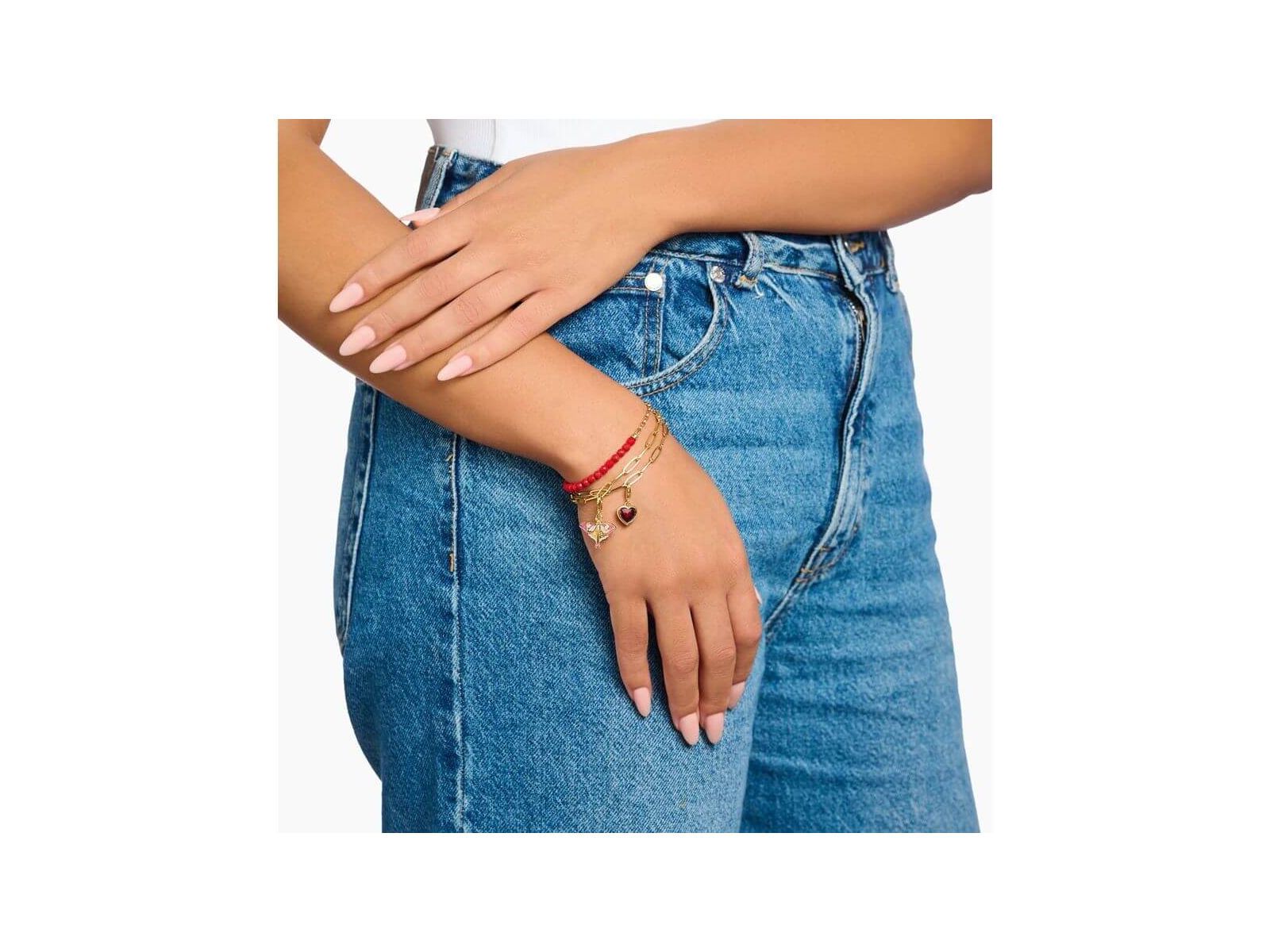 Femme portant un bracelet ajusté avec des perles rouges et un coeur, sur un fond en jeans.