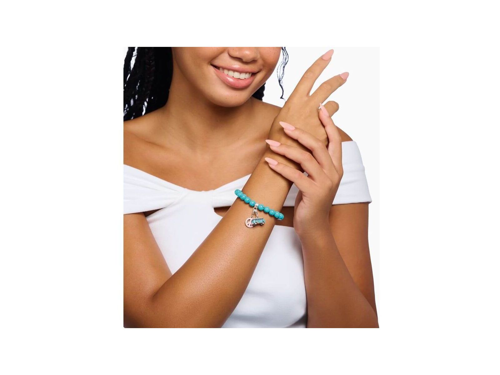 Femme souriante portant un bracelet charm avec perles turquoise et pendentif original en argent.