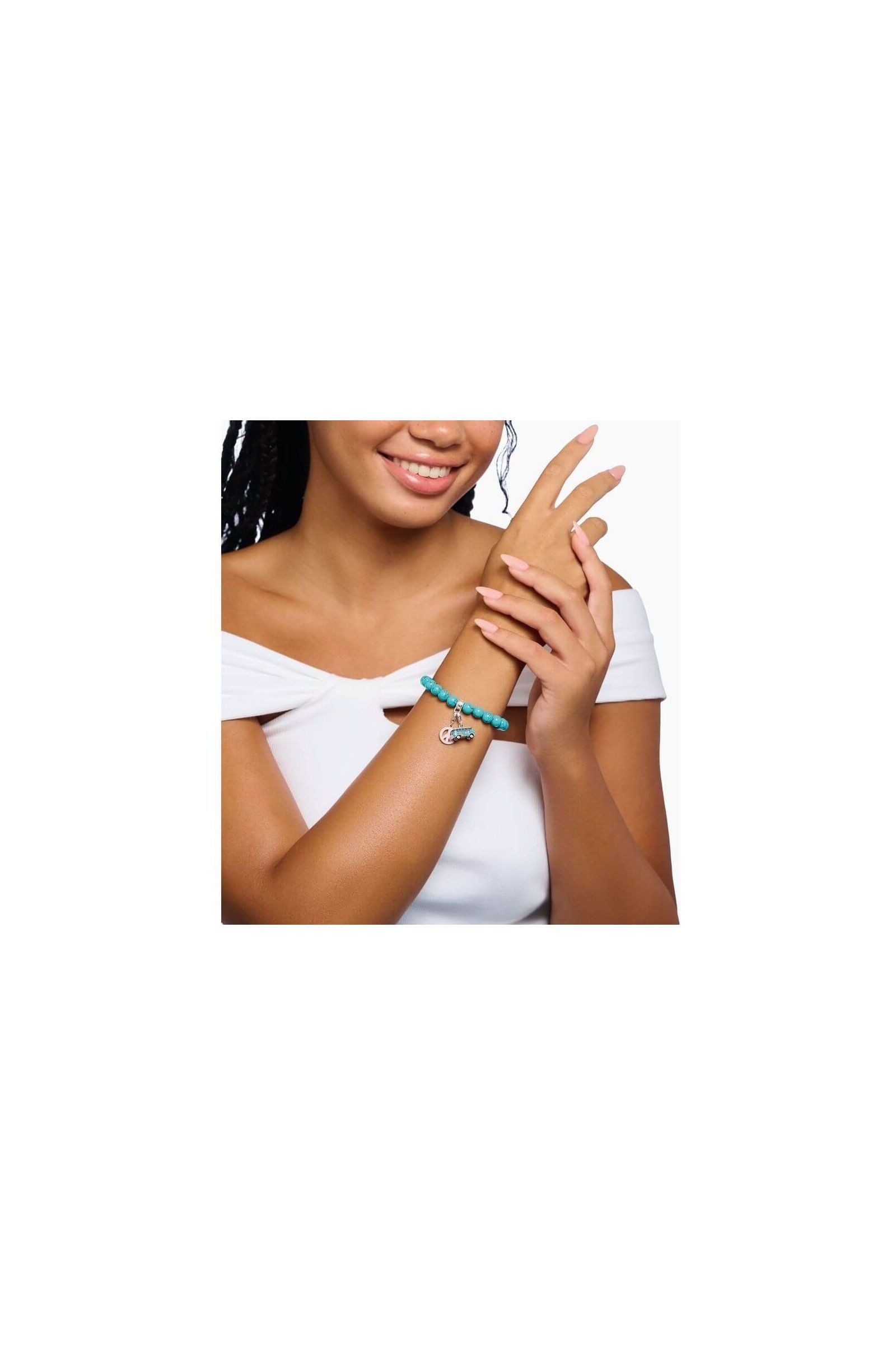 Femme souriante portant un bracelet charm avec perles turquoise et pendentif original en argent.
