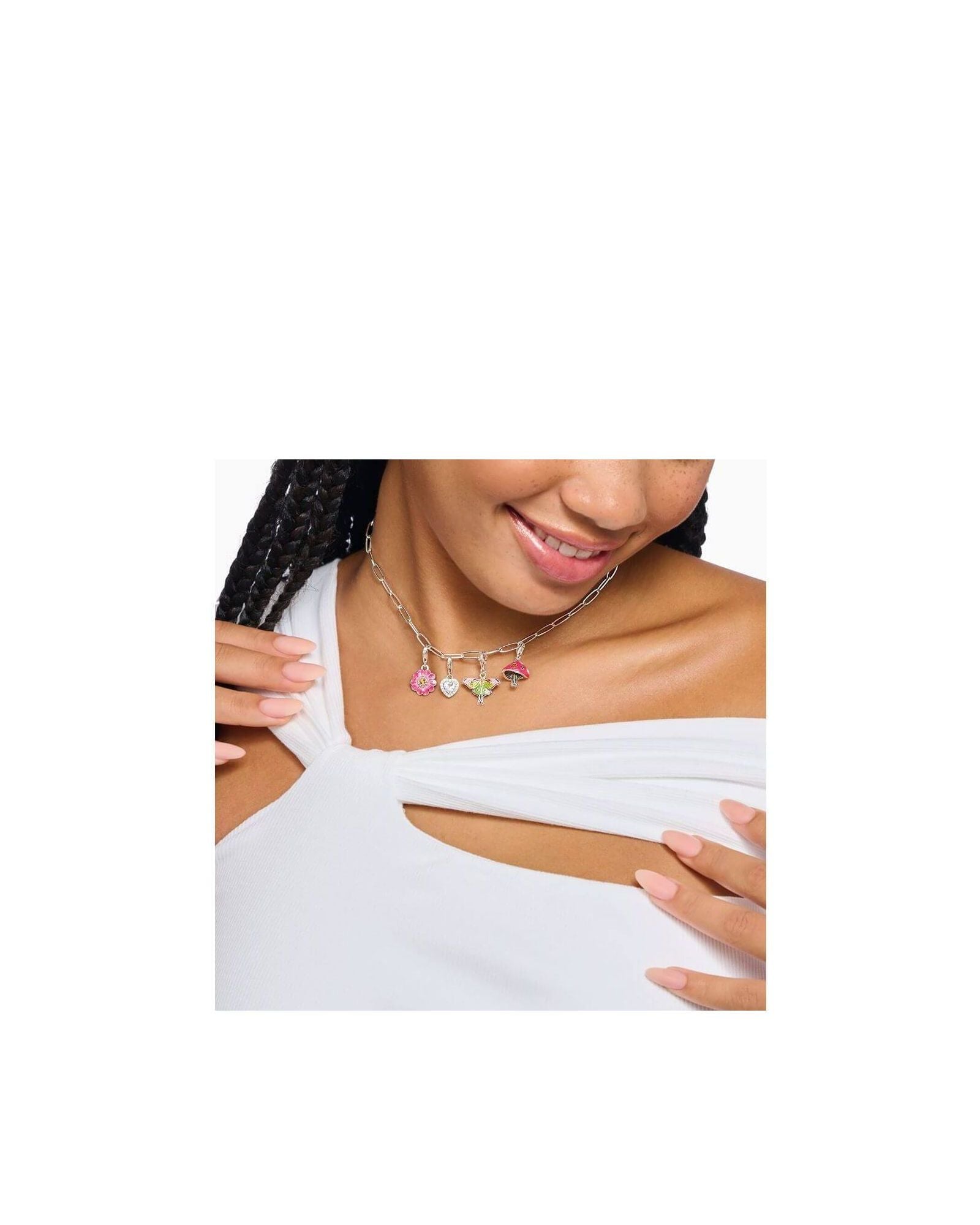 Femme souriante portant un collier en argent avec pendentifs champignon coloré et autres charms.