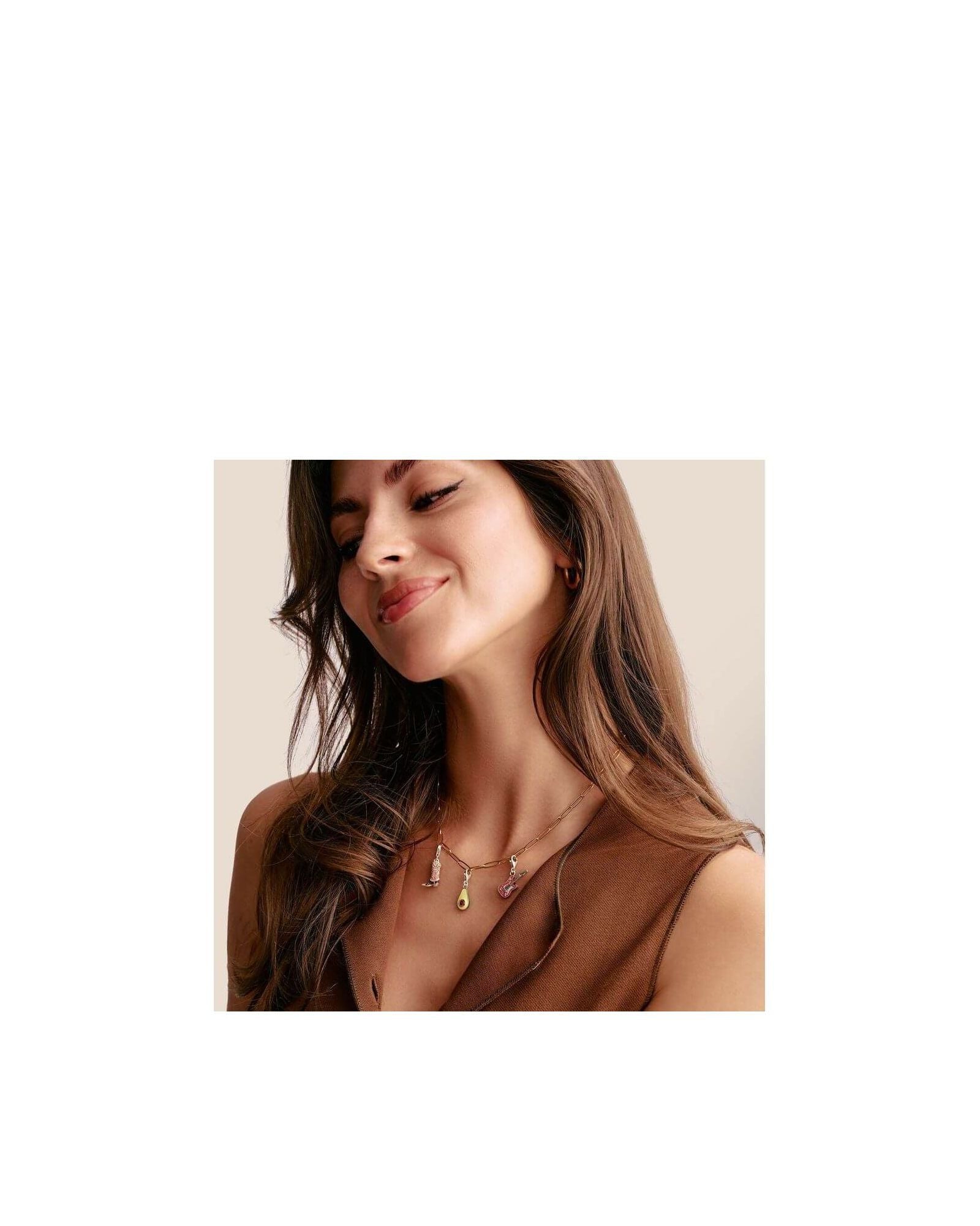 Femme souriante portant un pendentif charm avec des motifs colorés sur une chaîne délicate.