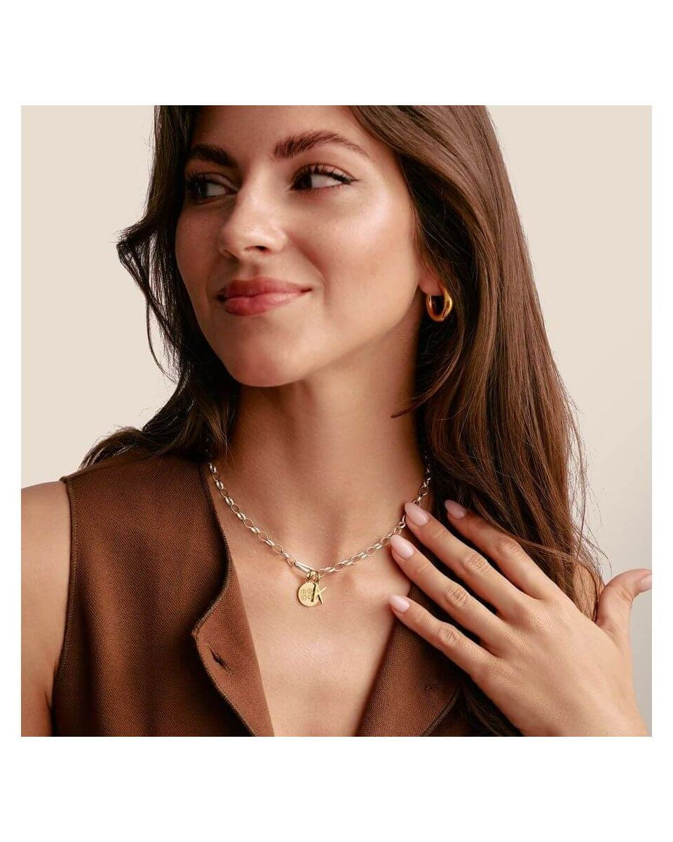 Femme portant un collier en argent avec un pendentif doré et des boucles d'oreilles en or, affichant un style élégant.