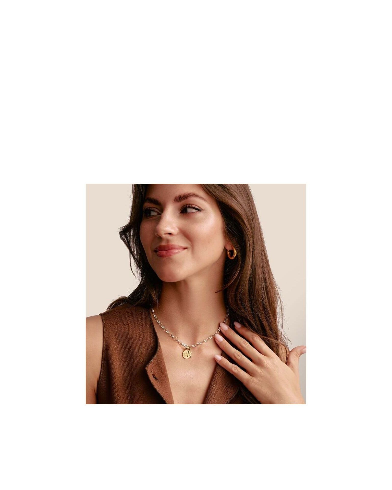 Femme portant un collier en argent avec un pendentif doré et des boucles d'oreilles en or, affichant un style élégant.