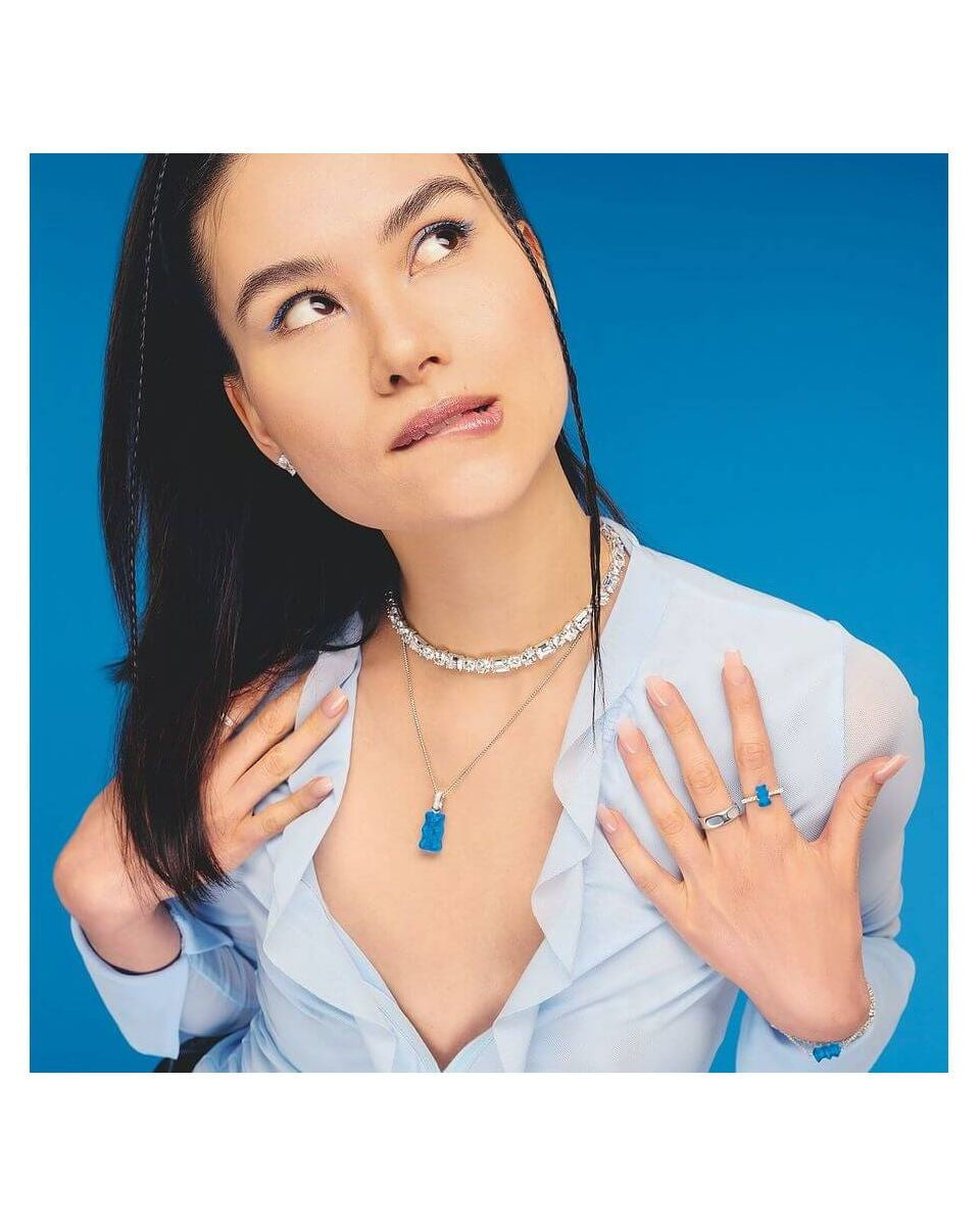 Modèle portant une chaîne à breloque Ours en argent et cristal bleu, avec accessoires assortis sur fond bleu.