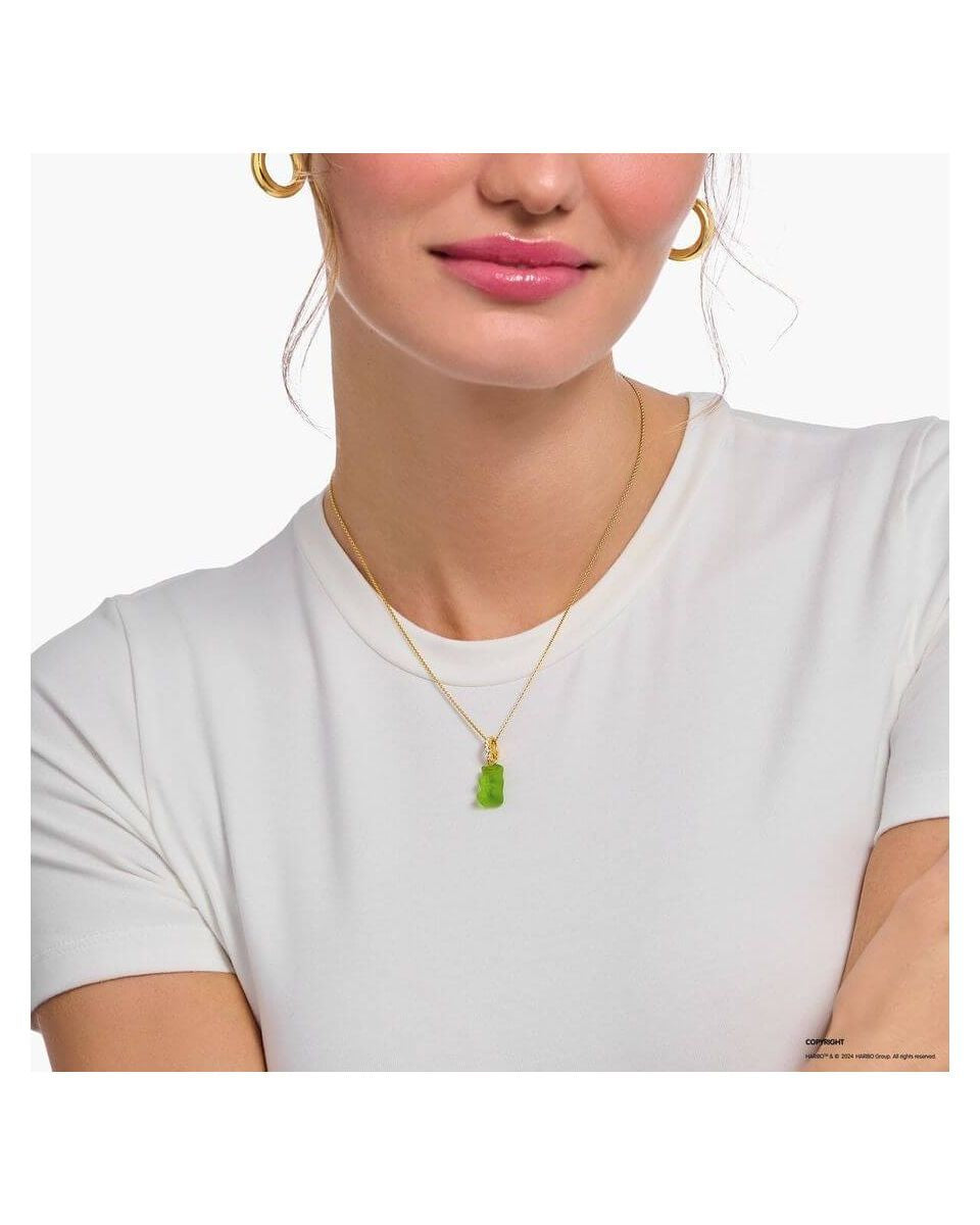 Gold chain necklace with green bear charm worn by a woman in a white shirt.