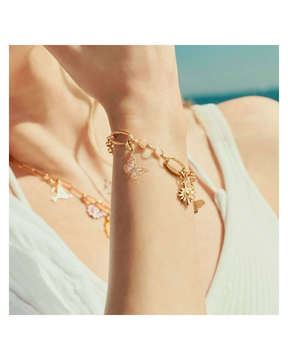 Pendentif charm papillon en plaqué or, porté sur bracelet délicat, capturant l'élégance estivale.