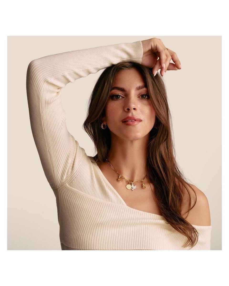 Modèle présentant un pendentif charm en or avec pierres blanches, dégageant élégance et style unique.