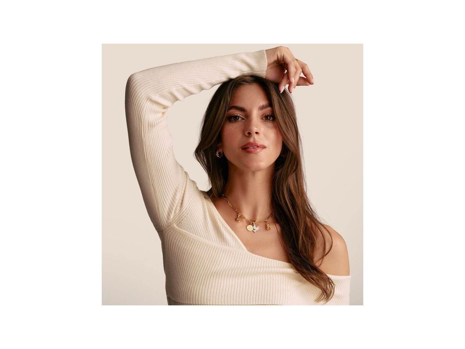 Modèle présentant un pendentif charm en or avec pierres blanches, dégageant élégance et style unique.