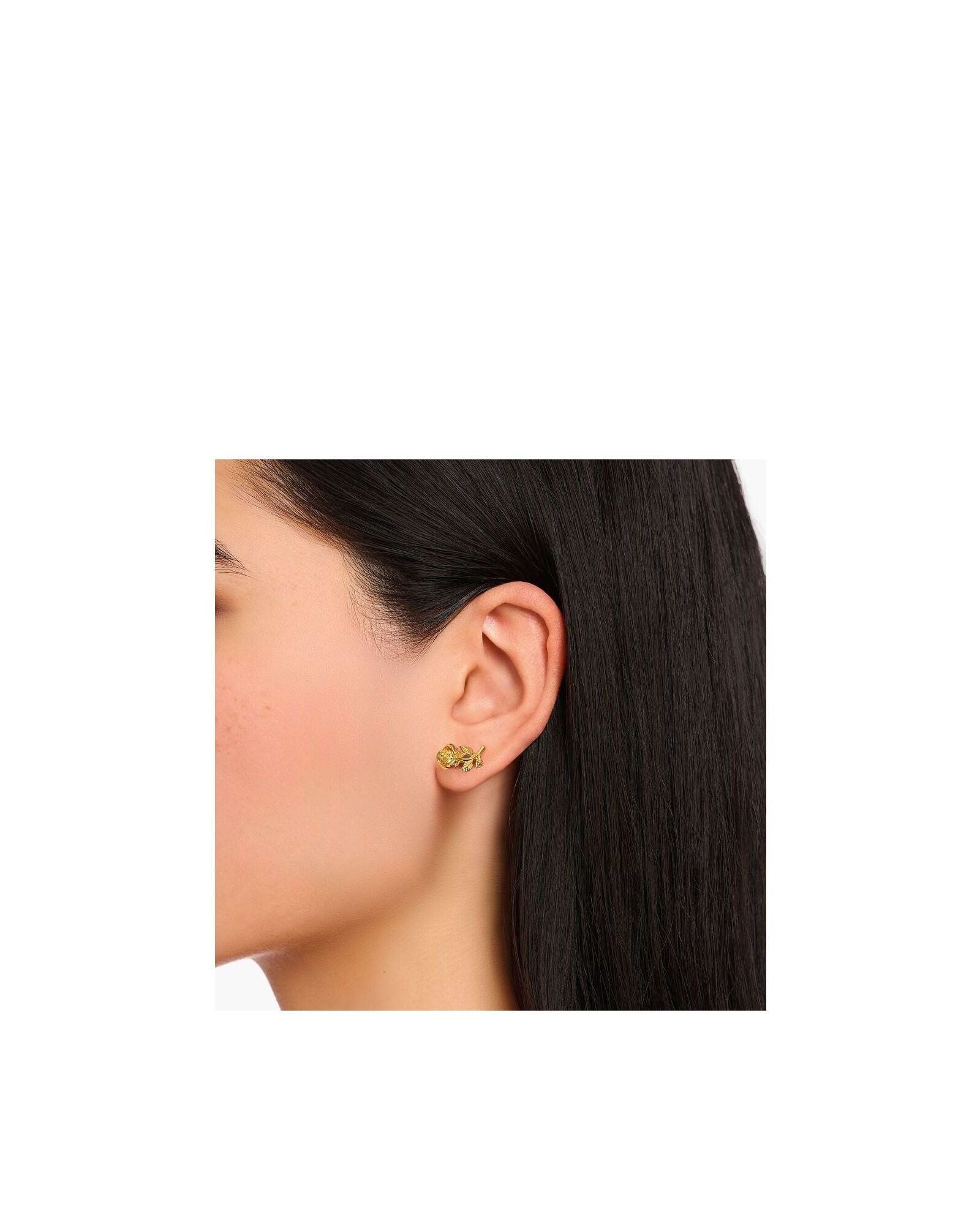 Clous d'oreilles Roses Romance plaqué or sur l'oreille d'une femme, avec un design en forme de rose en argent recyclé.