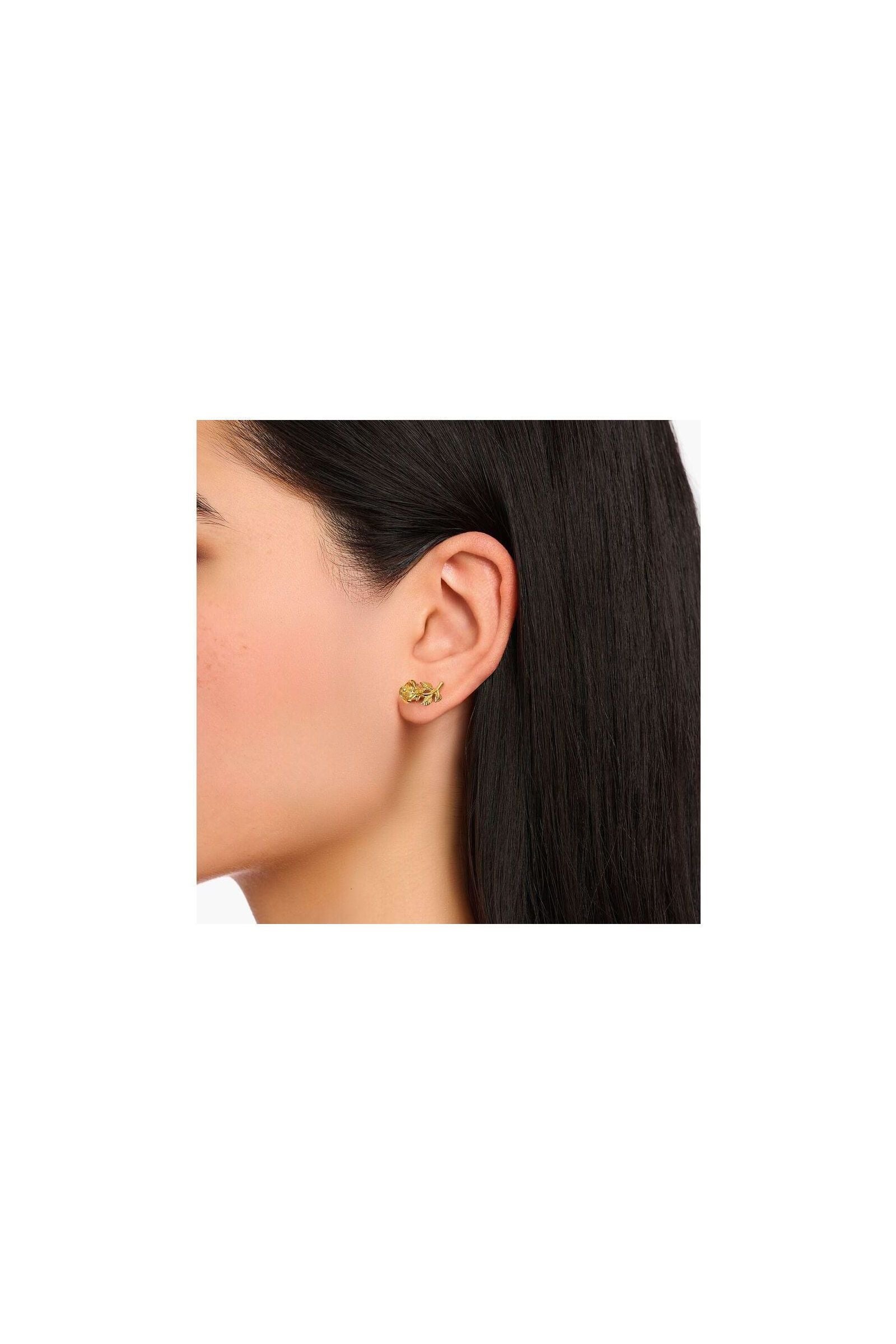 Clous d'oreilles Roses Romance plaqué or sur l'oreille d'une femme, avec un design en forme de rose en argent recyclé.