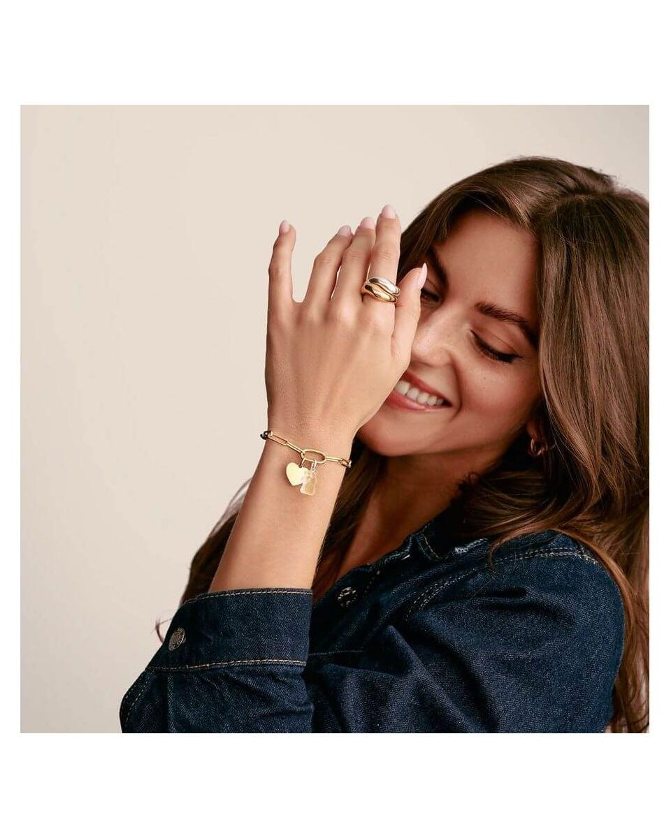 Femme souriante portant un pendentif charm cœur Connect plaqué or sur un bracelet en denim.