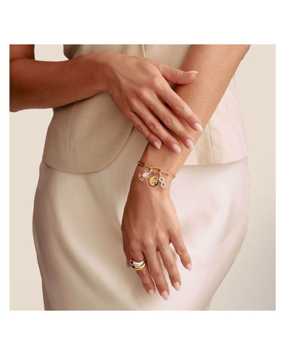 Femme portant un bracelet charm avec symbole infini et pendentifs en argent et or, mettant en valeur l'élégance et le style.