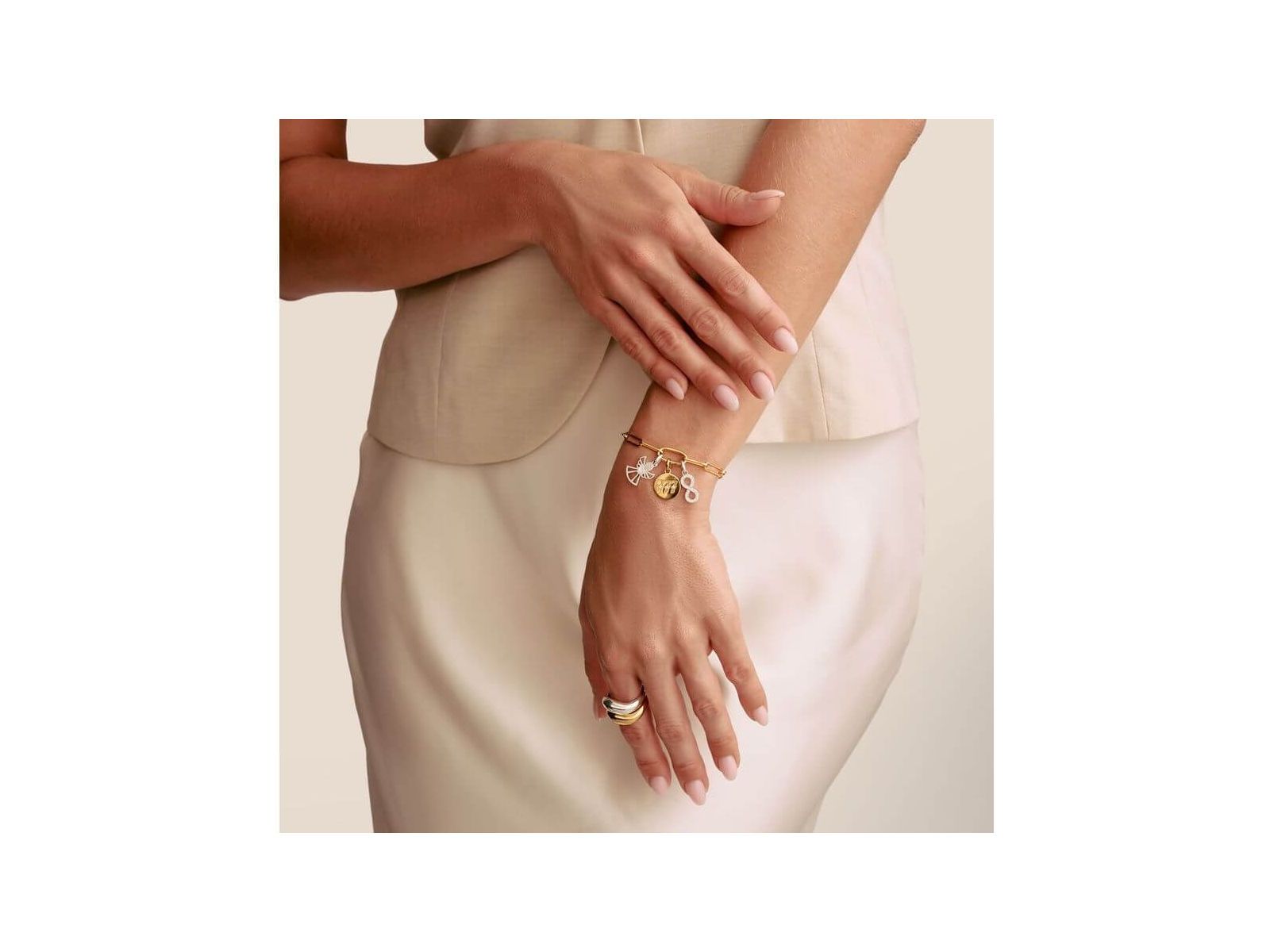 Femme portant un bracelet charm avec symbole infini et pendentifs en argent et or, mettant en valeur l'élégance et le style.