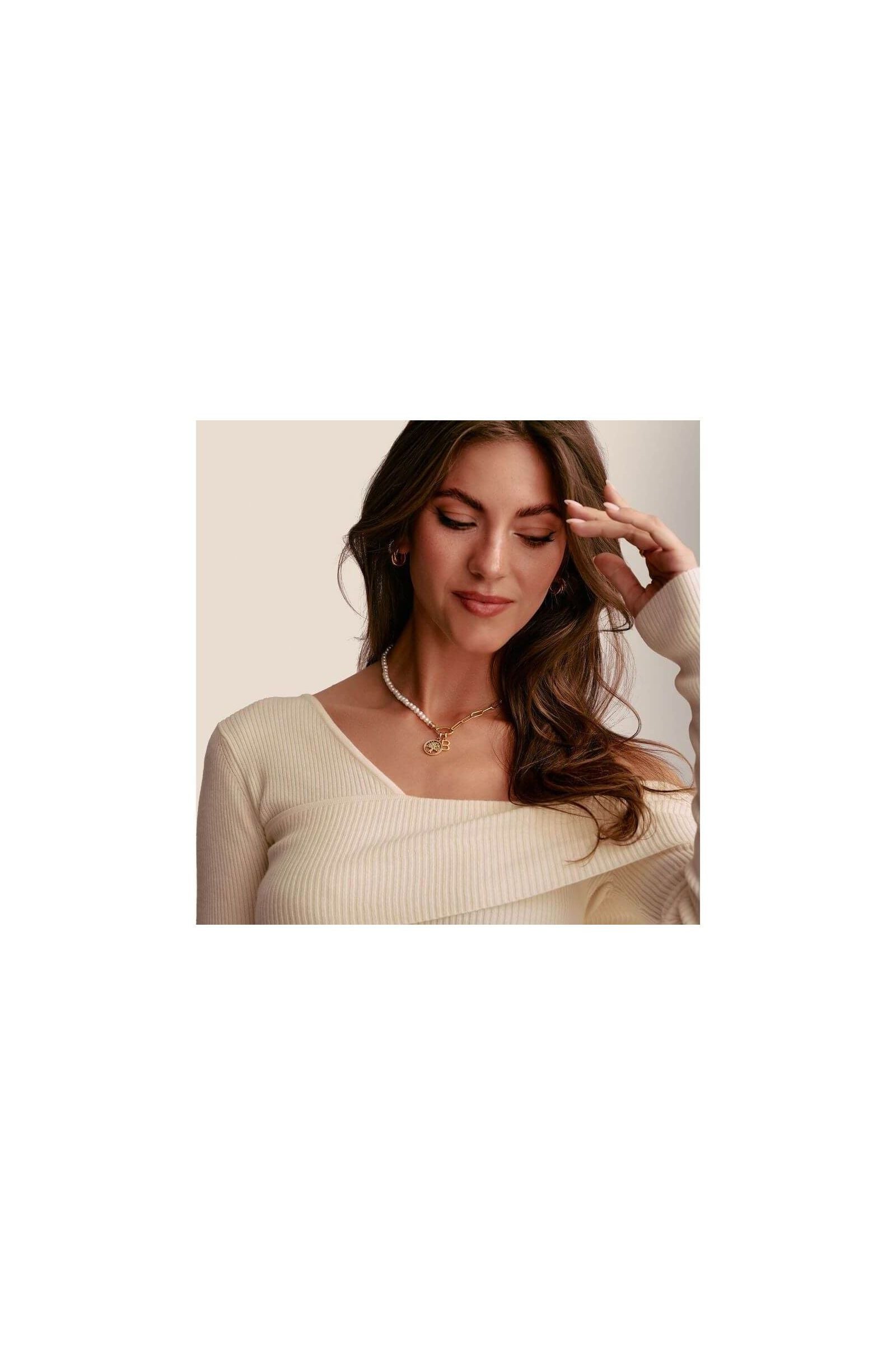 Model showcasing a delicate gold tree of love charm pendant adorned with white zirconium stones.