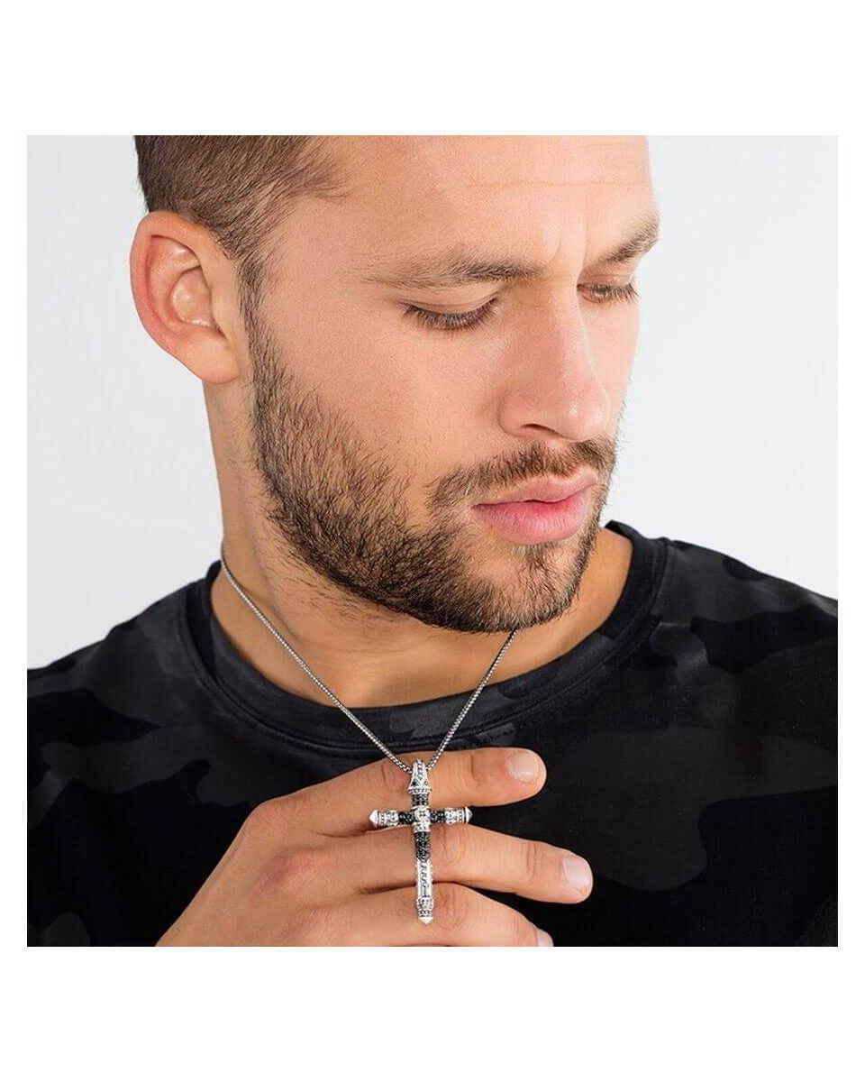 Homme portant un pendentif croix en argent avec une chaîne, affichant un look tendance et moderne.