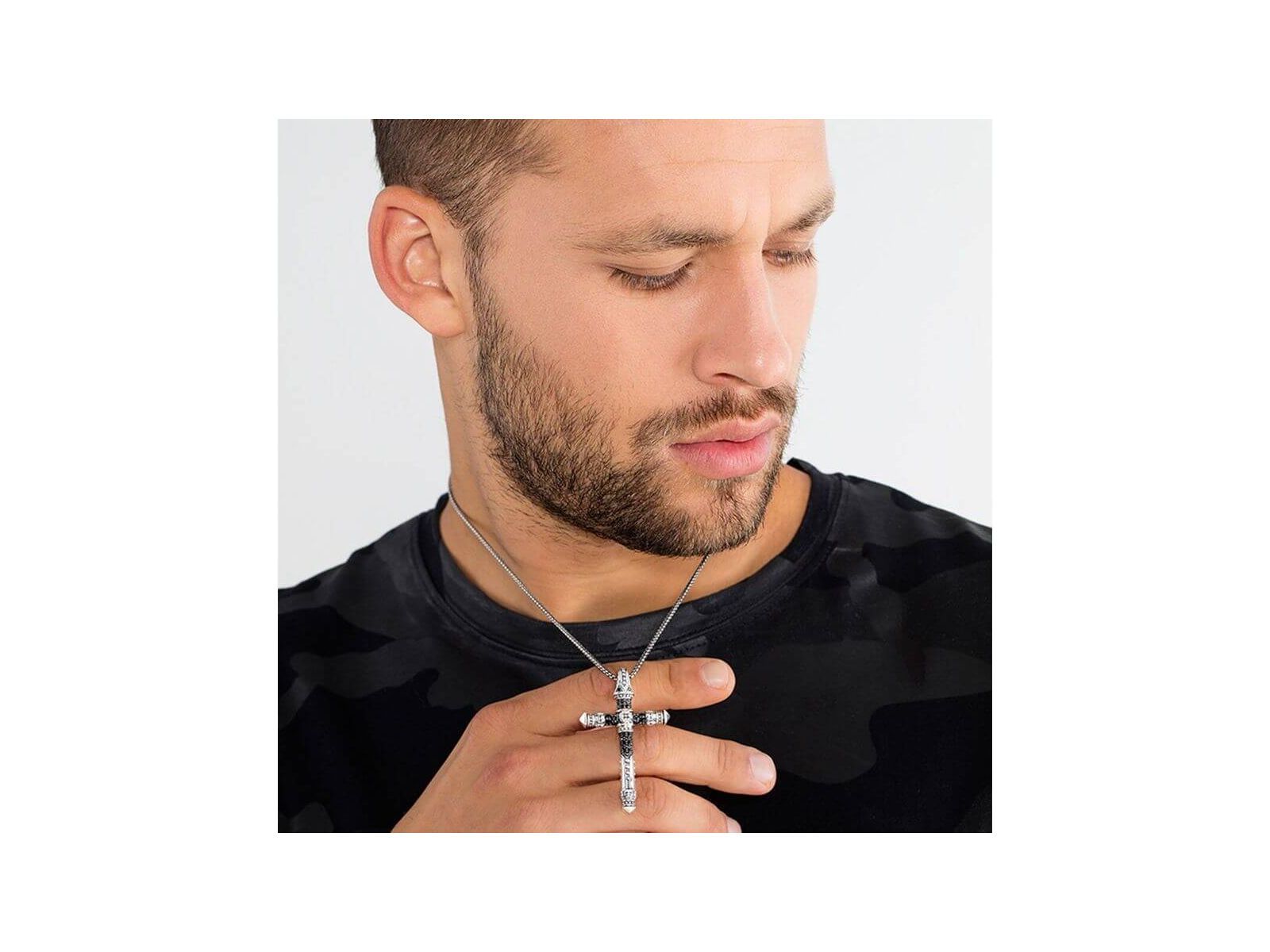 Homme portant un pendentif croix en argent avec une chaîne, affichant un look tendance et moderne.