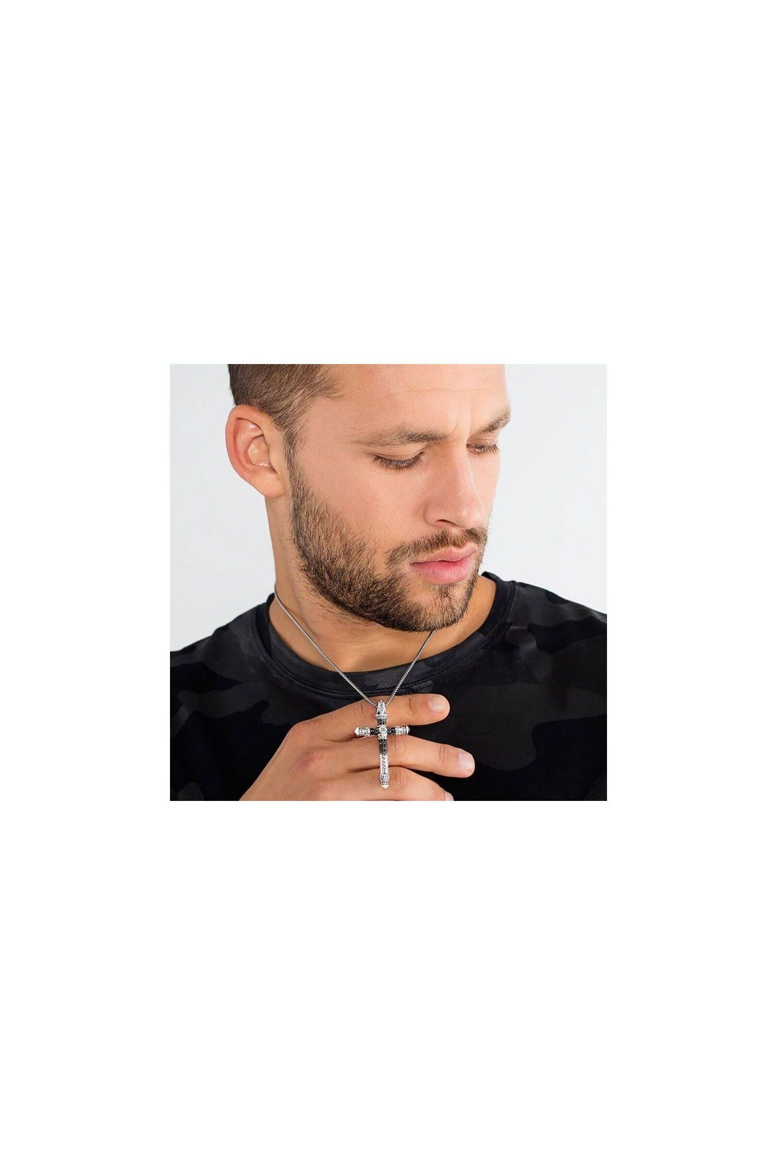 Homme portant un pendentif croix en argent avec une chaîne, affichant un look tendance et moderne.