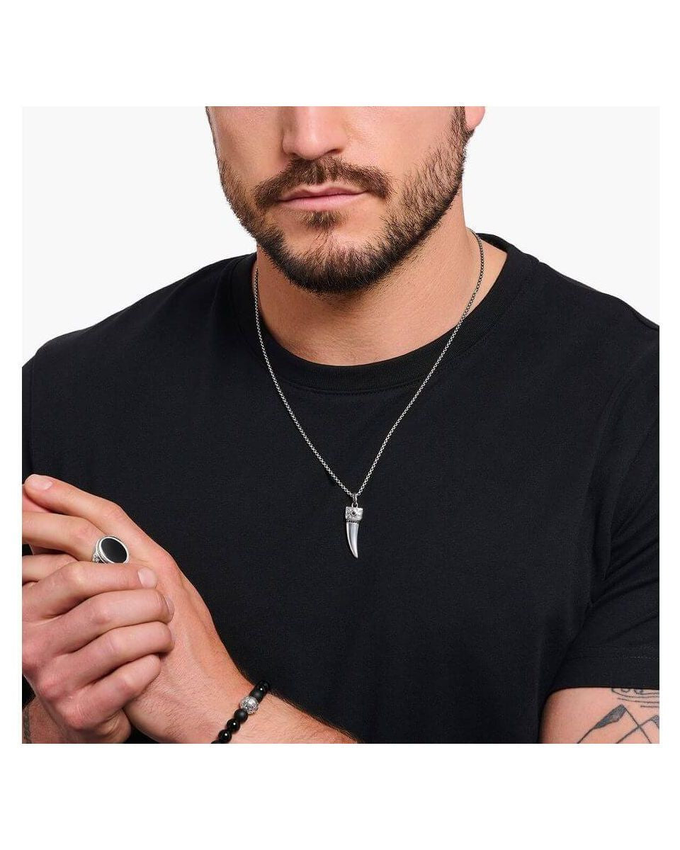 Homme portant une chaîne à breloque dent ornée de gemmes en argent noirci, style élégant.