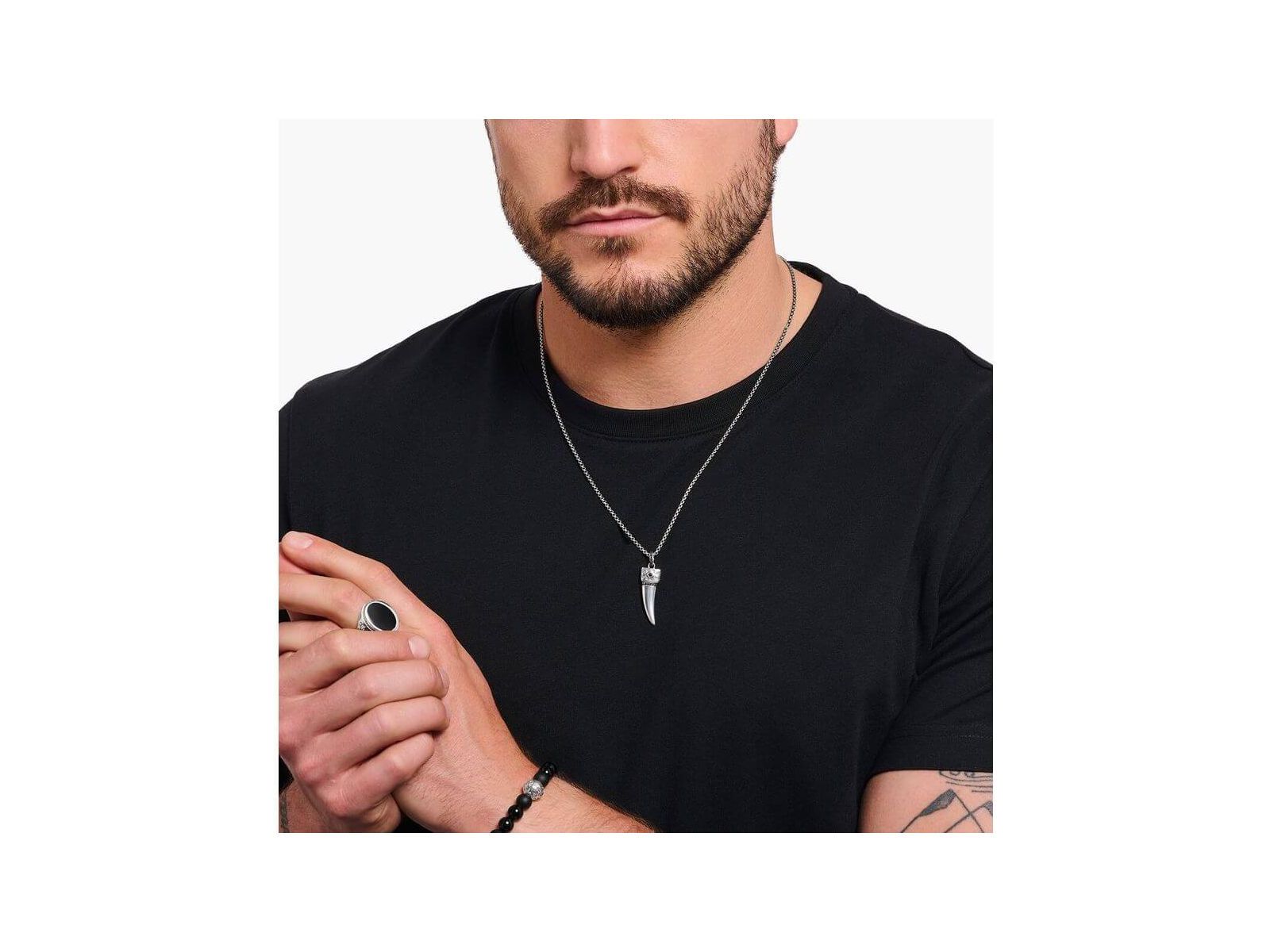 Homme portant une chaîne à breloque dent ornée de gemmes en argent noirci, style élégant.