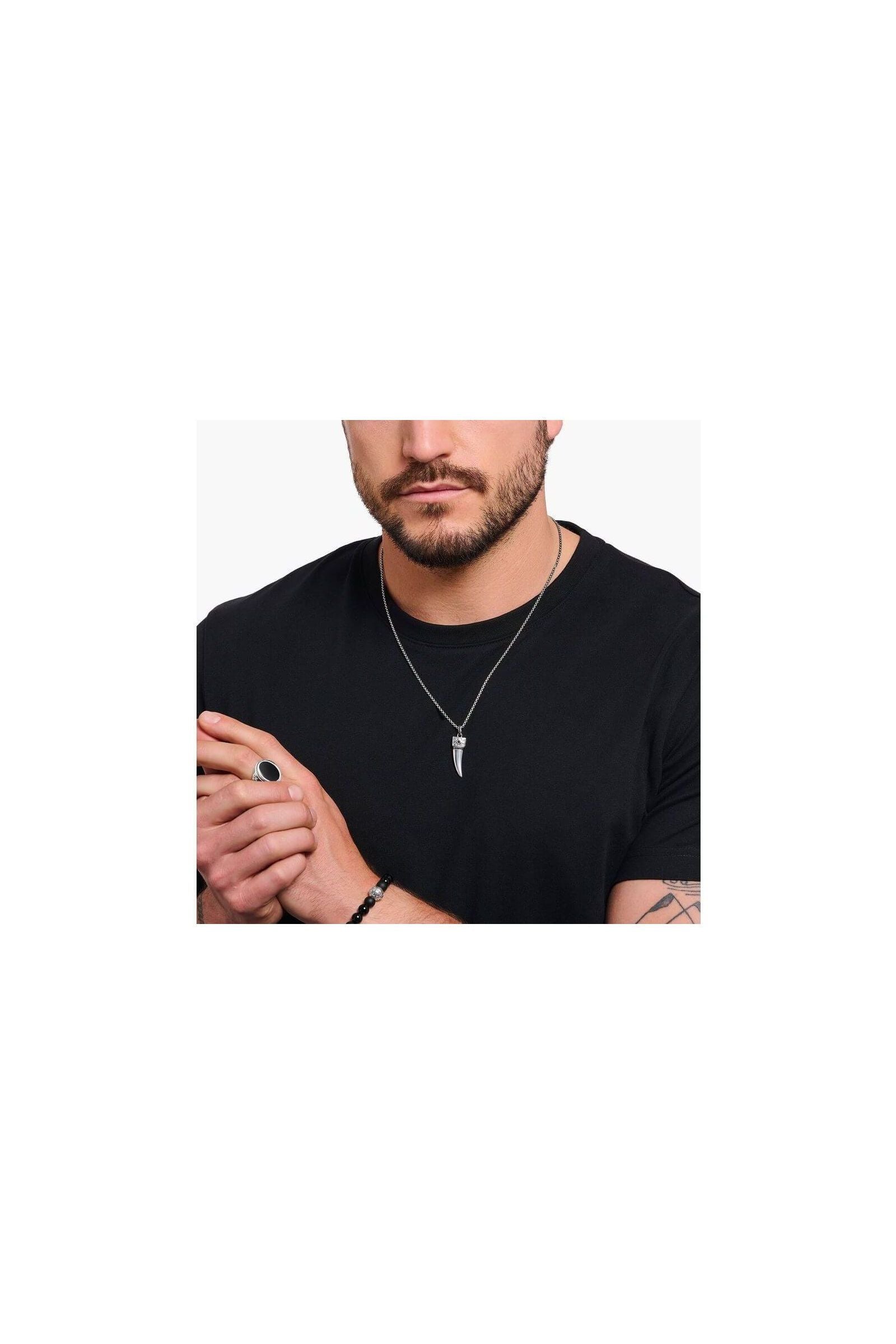 Homme portant une chaîne à breloque dent ornée de gemmes en argent noirci, style élégant.