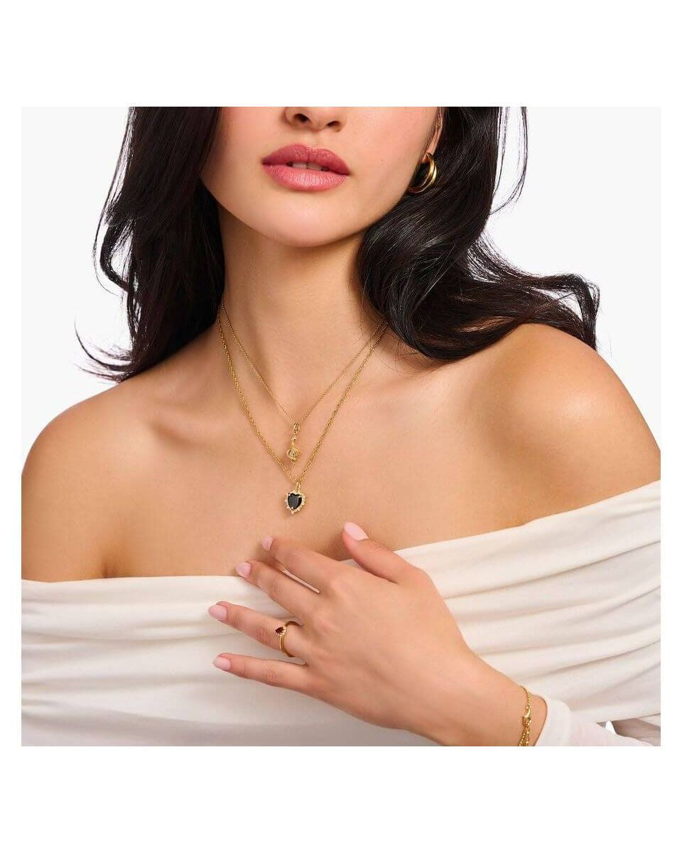 Femme portant une chaîne avec pendentif cœur en argent et or, mettant en valeur le style vintage et élégant.