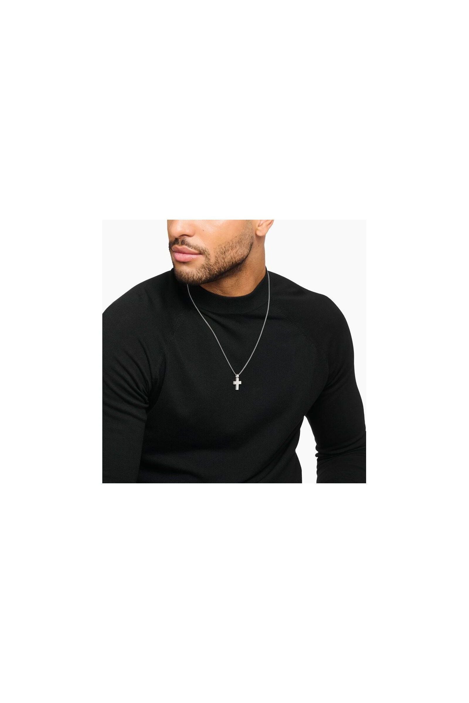 Homme portant un pendentif croix en argent 925 sur une chaîne, style minimaliste et élégant.