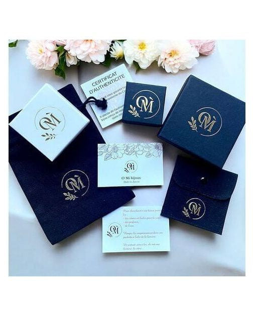 Image showcasing elegant jewelry packaging, including boxes and authenticity certificate, with floral accents.