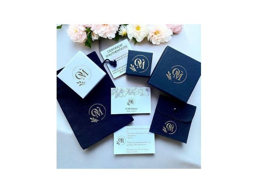 Image showcasing elegant jewelry packaging, including boxes and authenticity certificate, with floral accents.