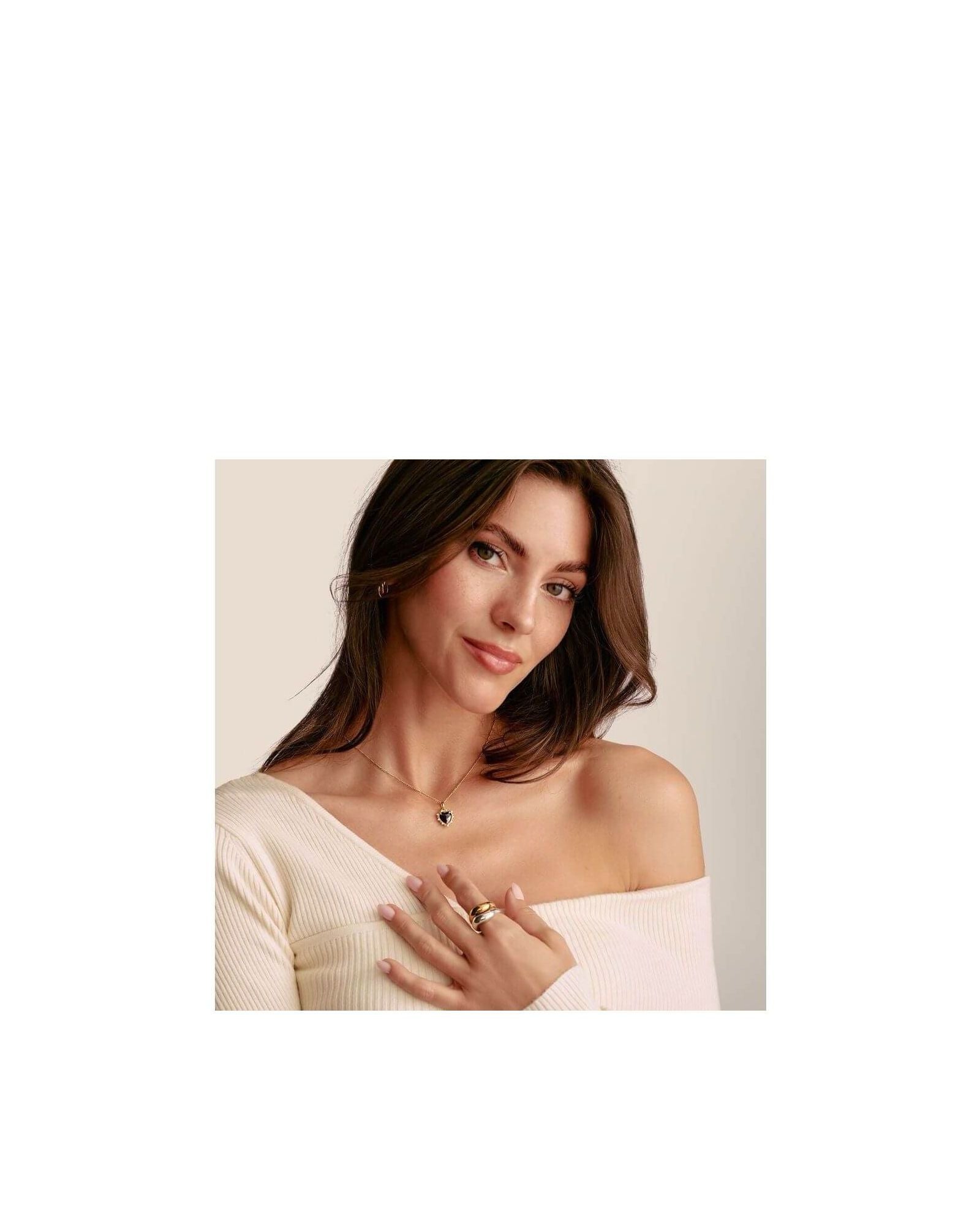 Femme portant un pendentif cœur vintage noir en argent plaqué or et des bagues, stylée et élégante.