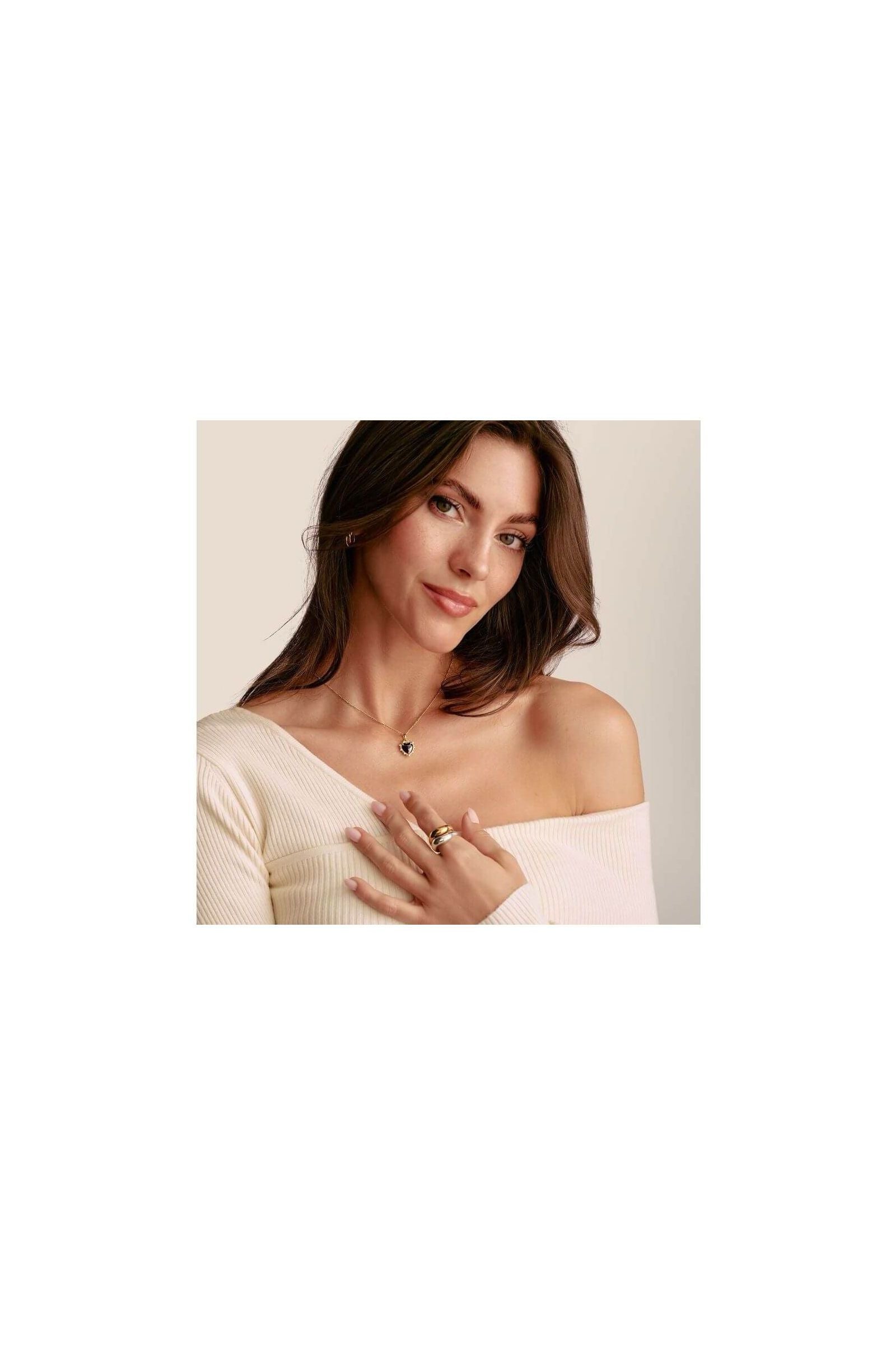 Femme portant un pendentif cœur vintage noir en argent plaqué or et des bagues, stylée et élégante.
