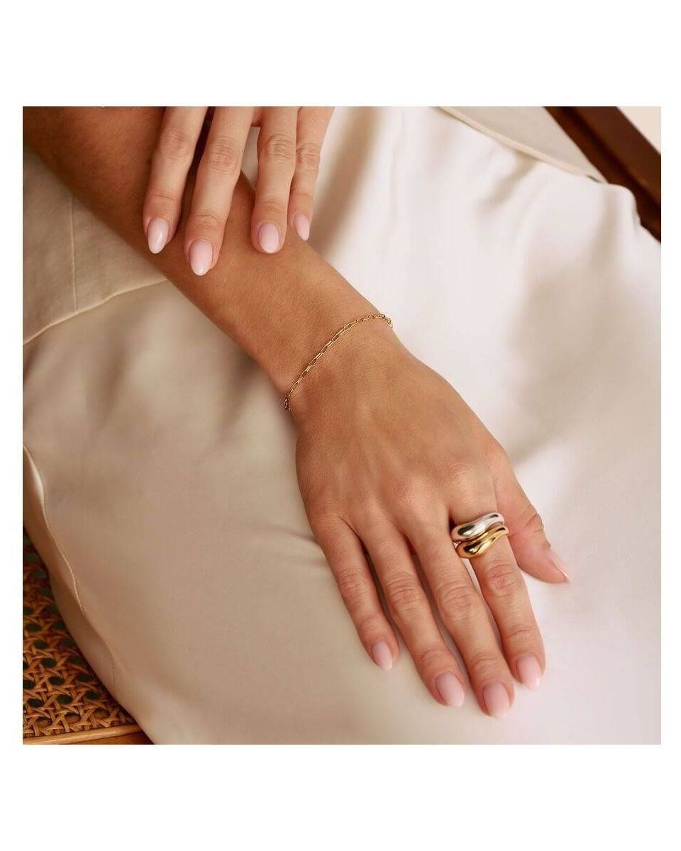 Bracelet charm Paperclip plaqué or sur poignet avec bague tendance, mettant en avant un style élégant et moderne.