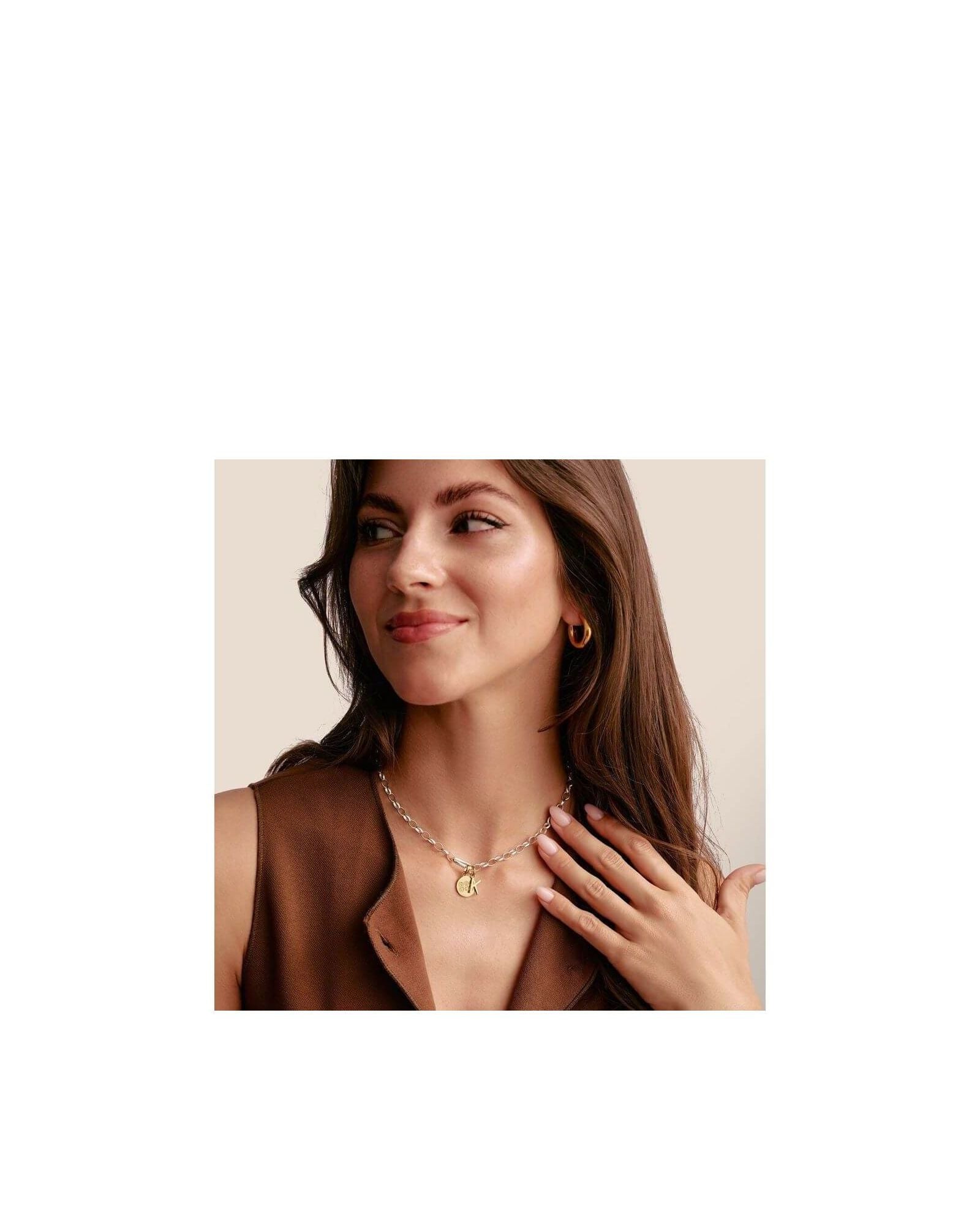 Femme souriante portant un collier chaîne avec un pendentif en or, affichant un style élégant et moderne.