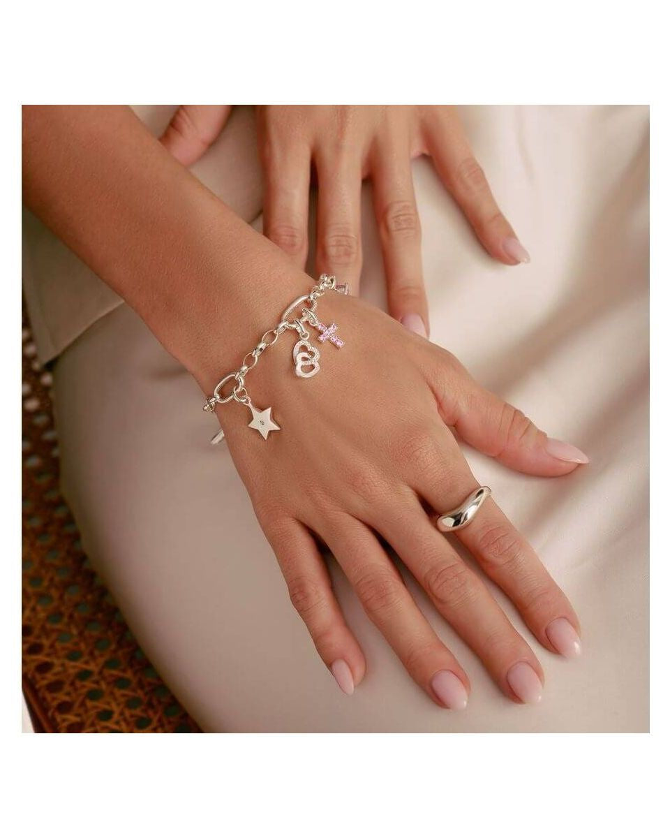 Bracelet charm argent avec étoile, croix et cœur, porté sur une main élégante, mettant en valeur un style unique.