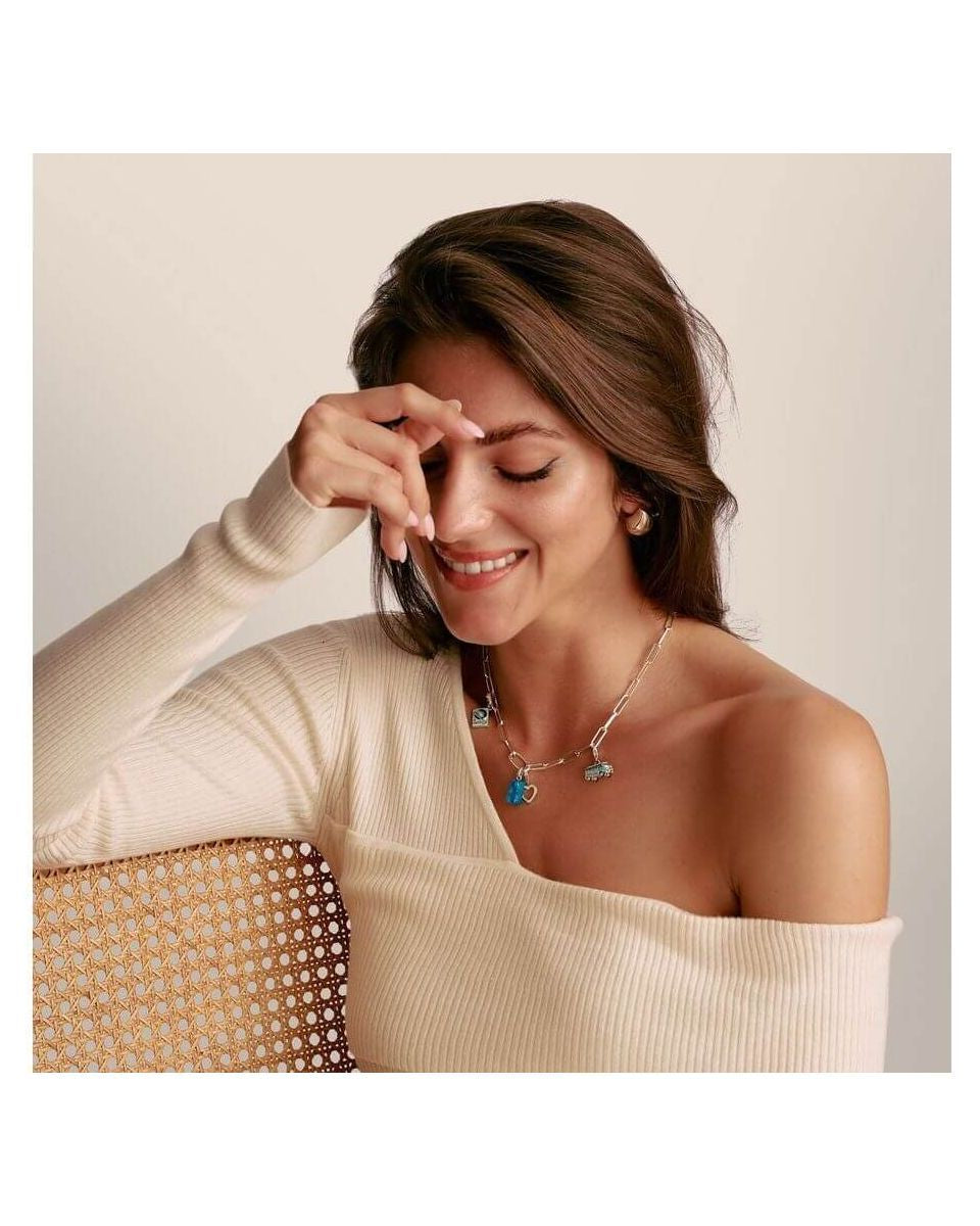 Woman wearing the Charm Ours d'Or pendant, smiling while showcasing its elegance on a stylish top.