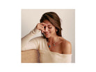 Woman wearing the Charm Ours d'Or pendant, smiling while showcasing its elegance on a stylish top.