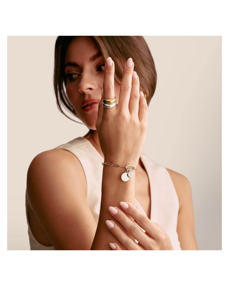Femme portant un bracelet avec pendentif médaille Connect Charm en argent recyclé, mettant en valeur un style élégant.