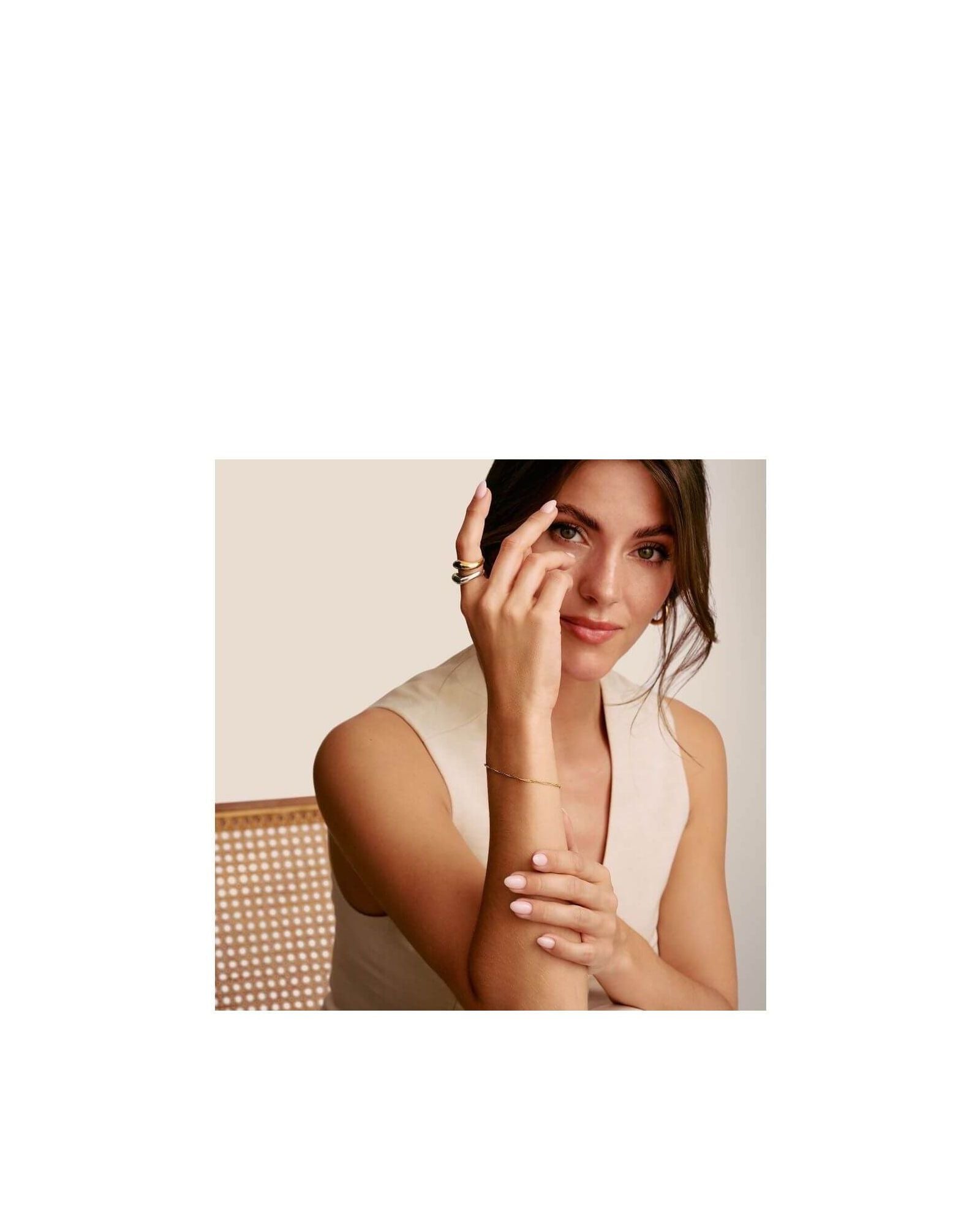 Model showcasing a charm bracelet design featuring 18k gold plating and a spiral filigree pattern.